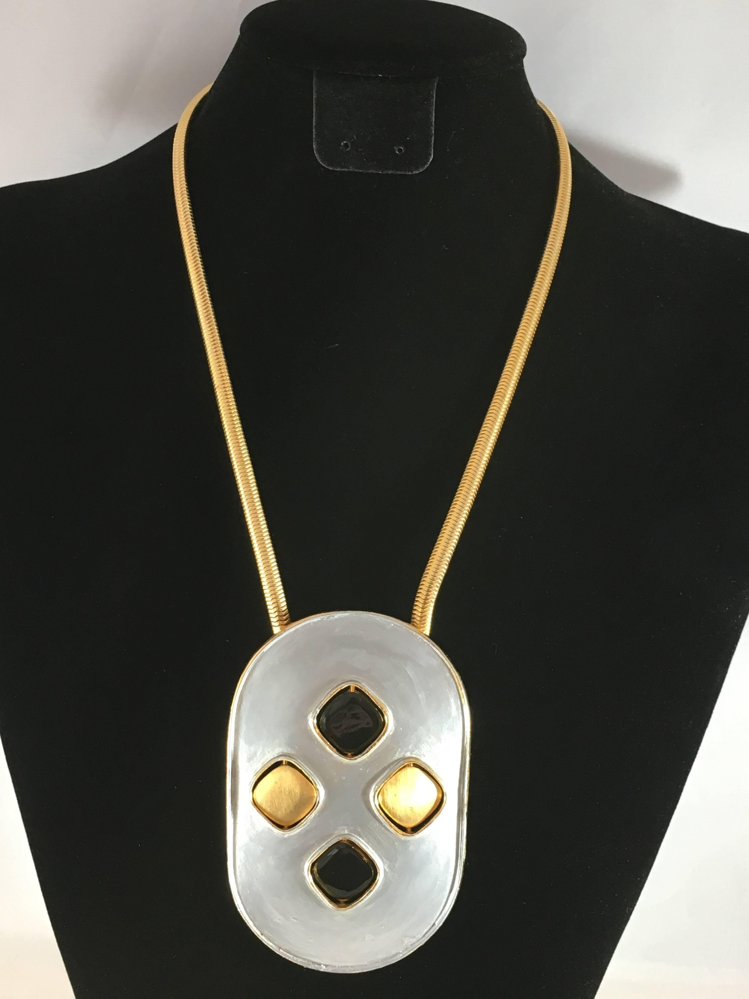 This is a Pierre Cardin pendant necklace from the 1960s. The disks on the pendant are changeable - one side is gold colored and the other side is black enamel. The disks can be worn in many different combination - thus changing the look of the