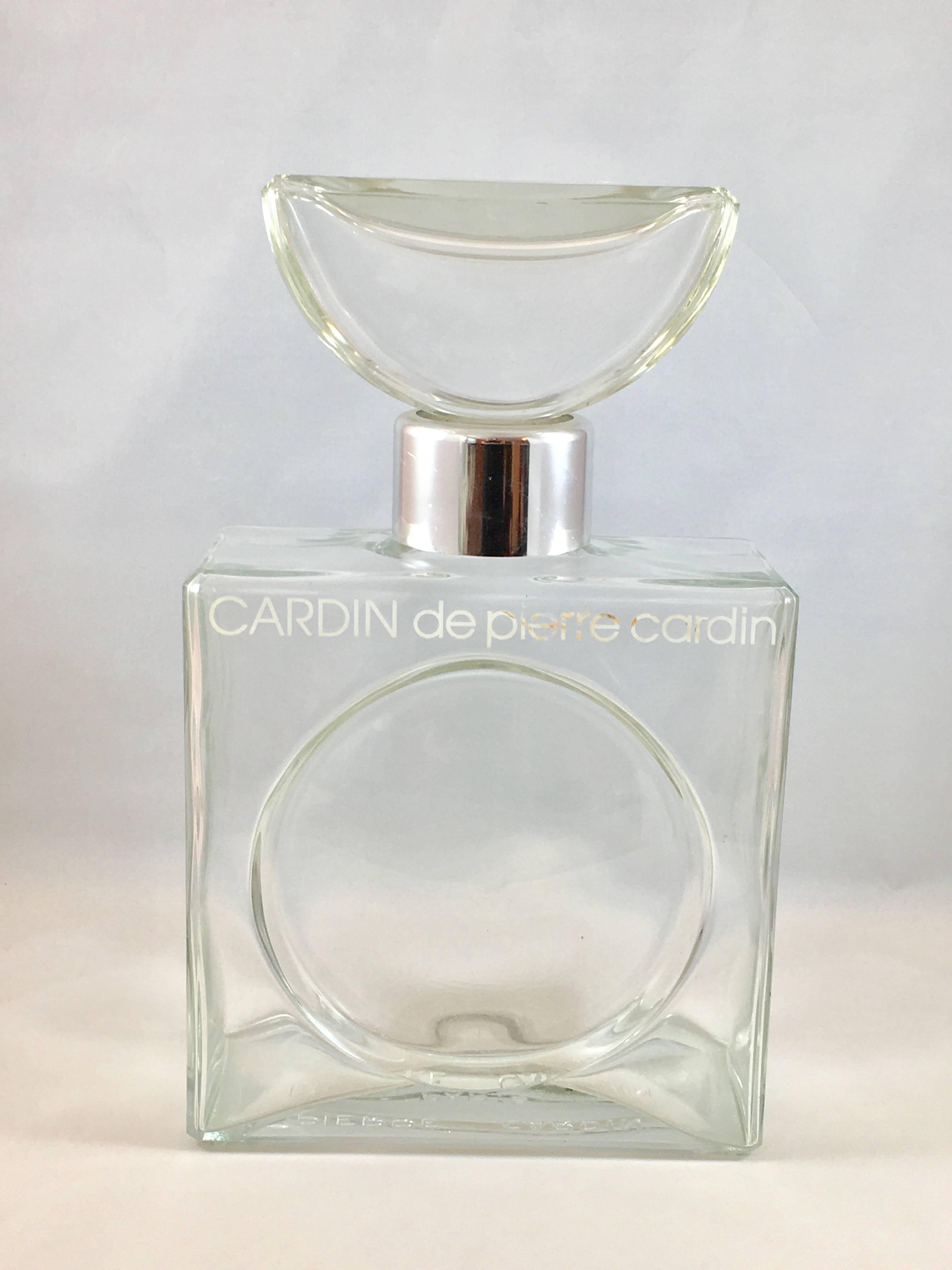 This is a huge Pierre Cardin glass perfume display bottle for a perfume called, 'Cardin'. Cardin was the first fragrance to be produced by Pierre Cardin. It was launched in 1976. 

The bottle has 'Cardin de Pierre Cardin' stenciled in white on the