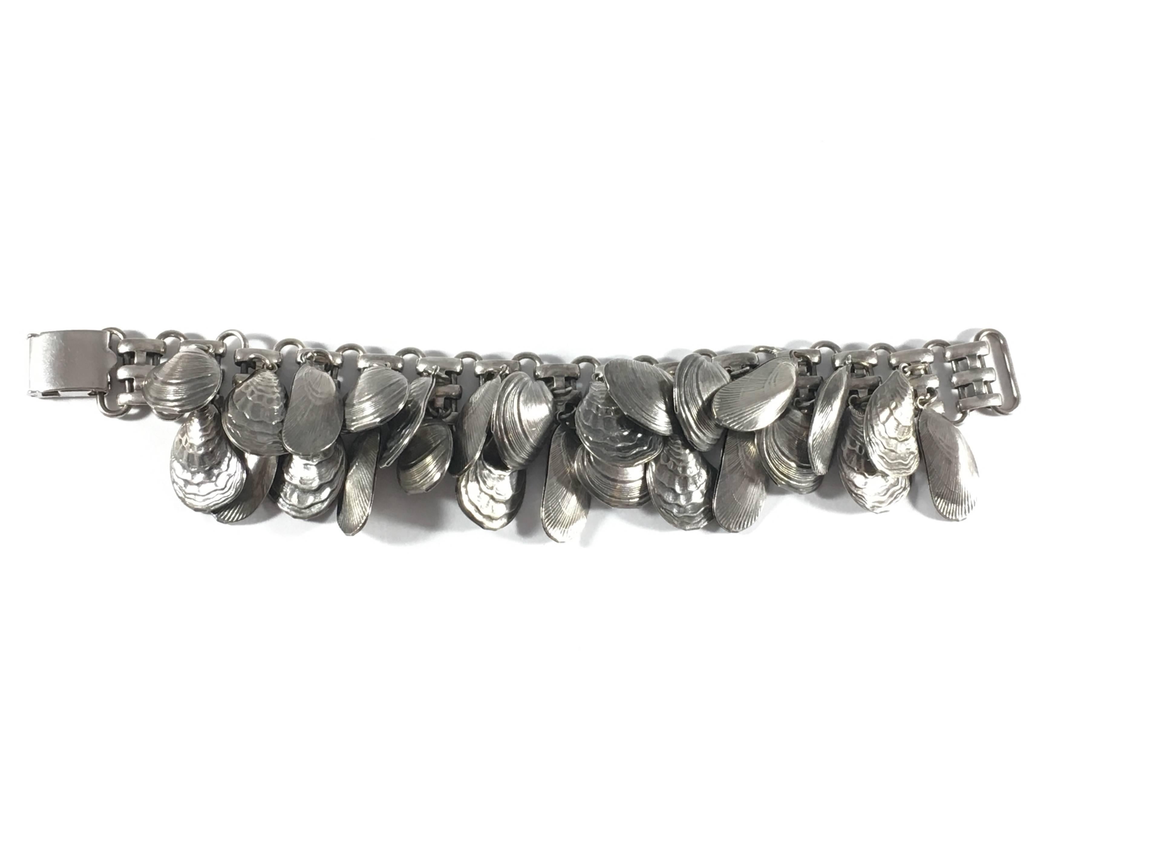 This is an amazing Napier silver-tone shell charm bracelet from the 1950s. The silver-tone ones are harder to find than the gold-tone ones. It measures 7 1/2 inches long and 1 1/2 inches wide at its widest point. There are three different kinds of