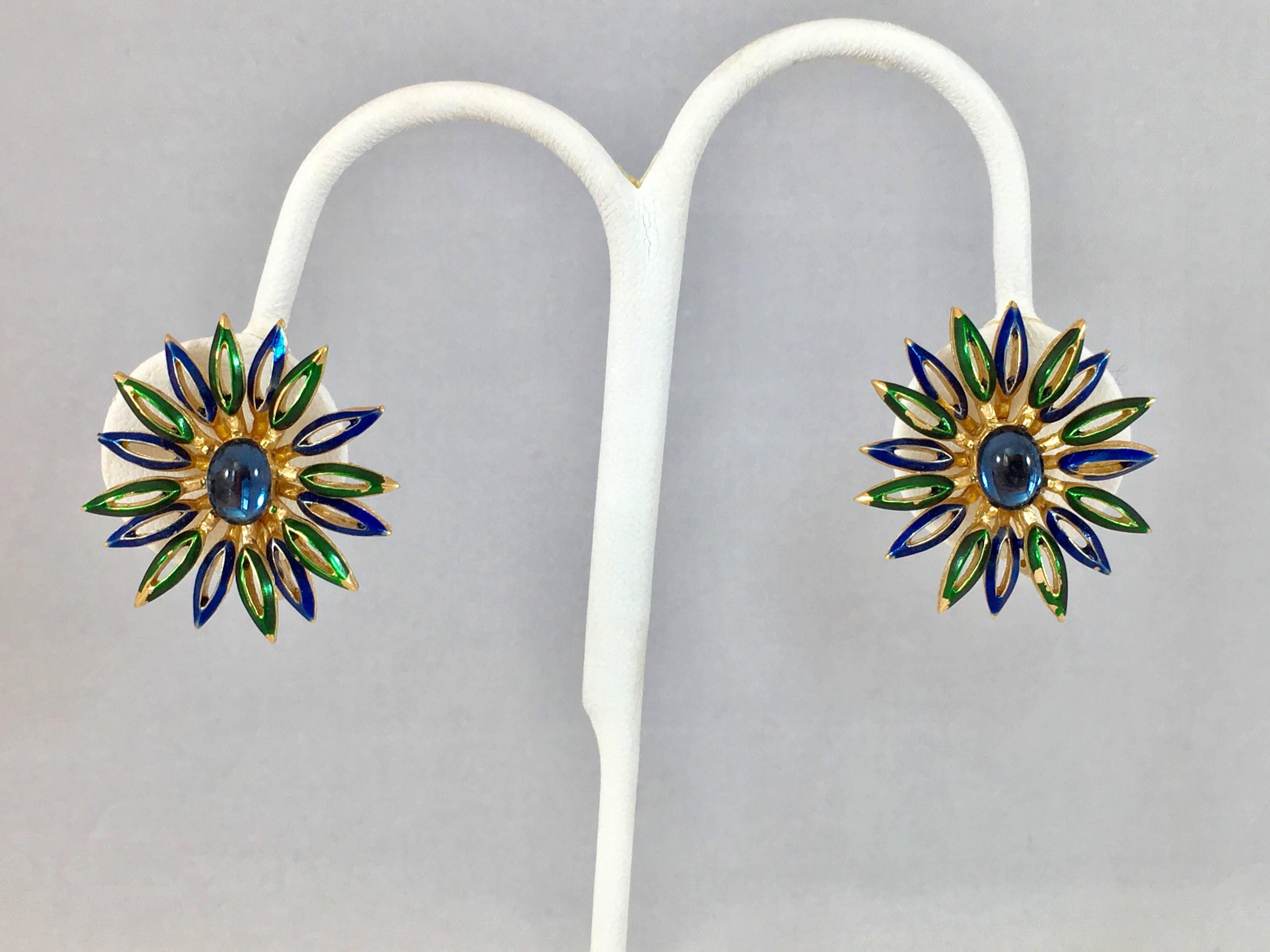 This is a fun pair of 1960s Trifari flower clip-on earrings. They are made out of goldtone metal, have blue glass centers and enameled blue and green petals. They measures 1 1/8 inches long by 1 1/16 inches wide. They are in excellent condition.