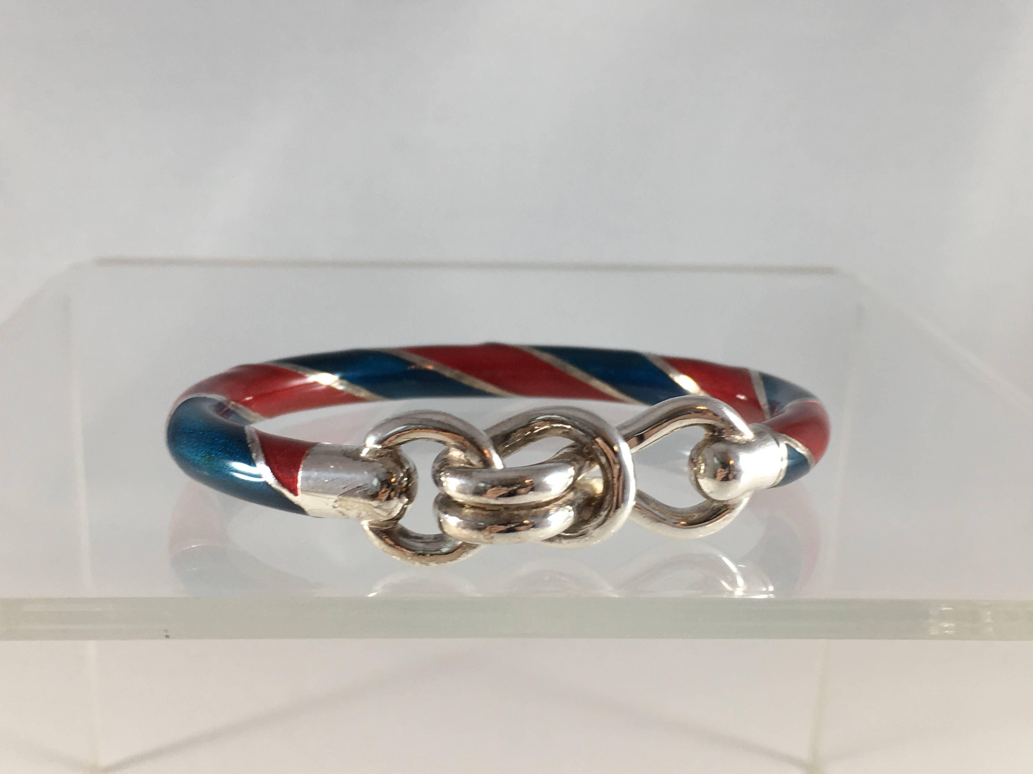This is an amazing 1980s vintage sterling silver Gucci bracelet with red and blue enamel. It has a knot-like closure at the font that opens and allows the wearer to put it on. The inner circumference measures 6 3/8 inches. The width of the bracelet