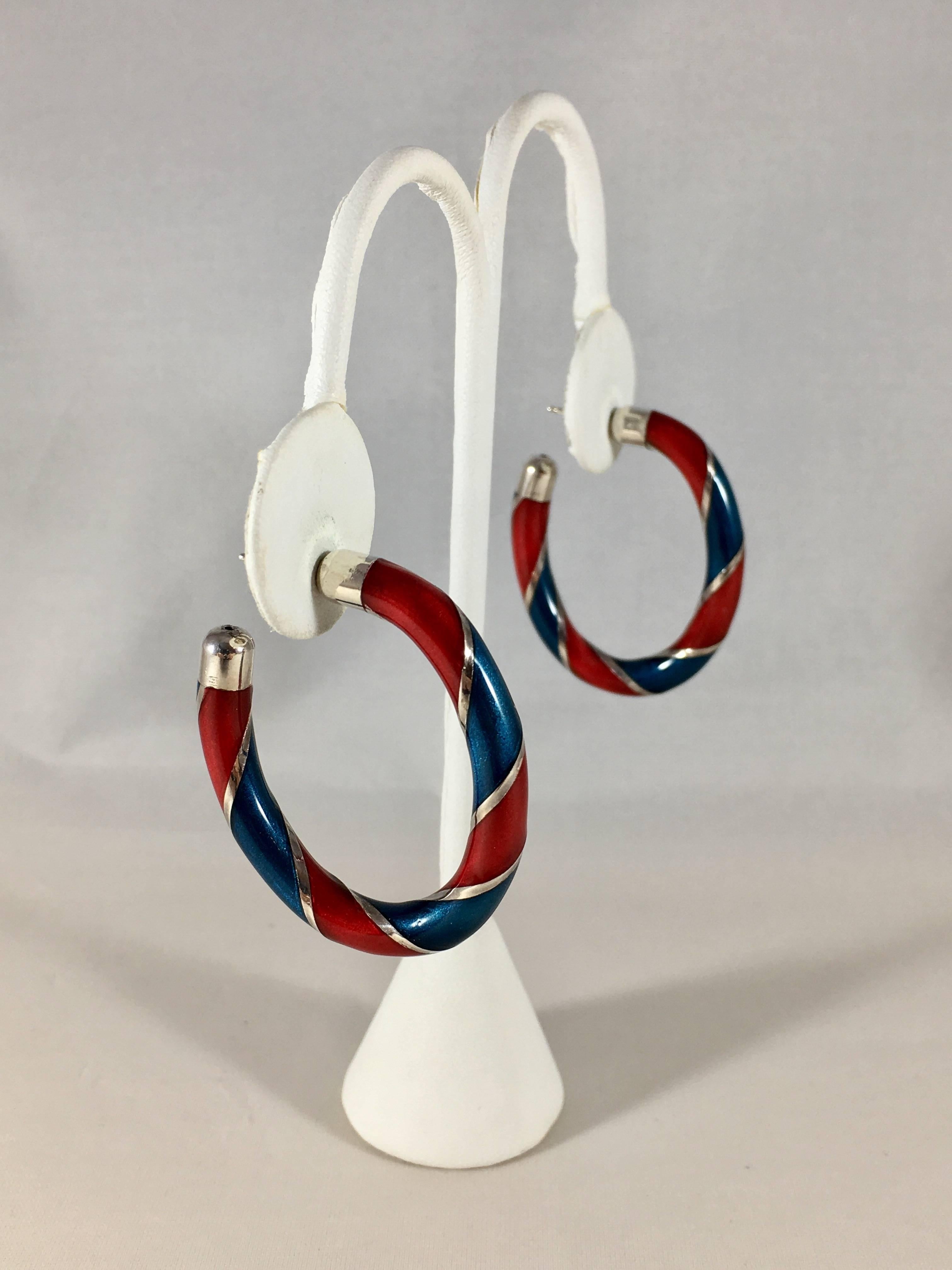 These are an amazing 1970s sterling silver and enamel pair of Gucci hoop earrings. They are striped with red and blue enamel over silver. They measure    1 5/8 inches long x 1 3/8 inches wide. The width is 3/16 inches. The earrings are in excellent
