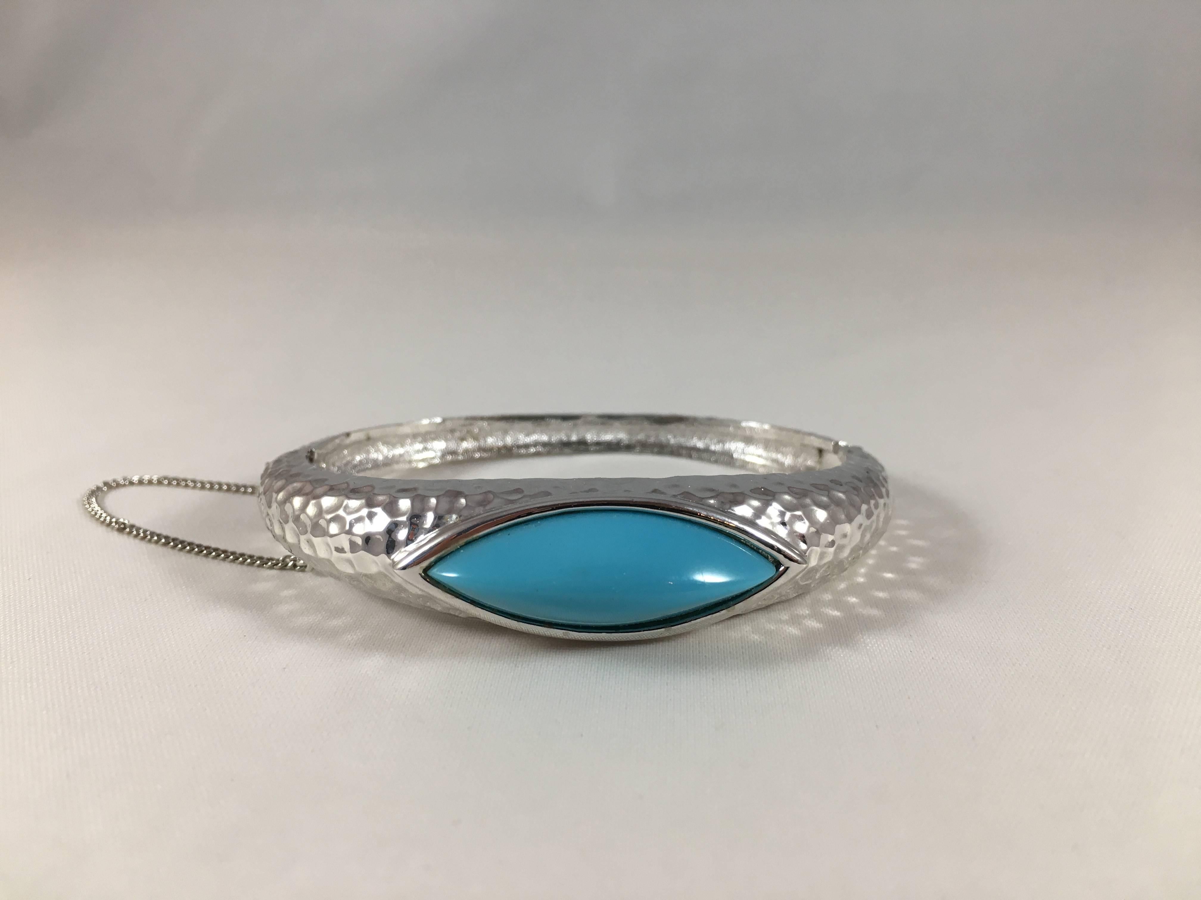 This is a Panetta bracelet from the 1970s with original tags. It features a faux turquoise cabochon stone set in a hammered silver-tone metal bracelet. It fastens at the side and is marked 'Panetta' on the inside (see image #7). It measures a 1/2