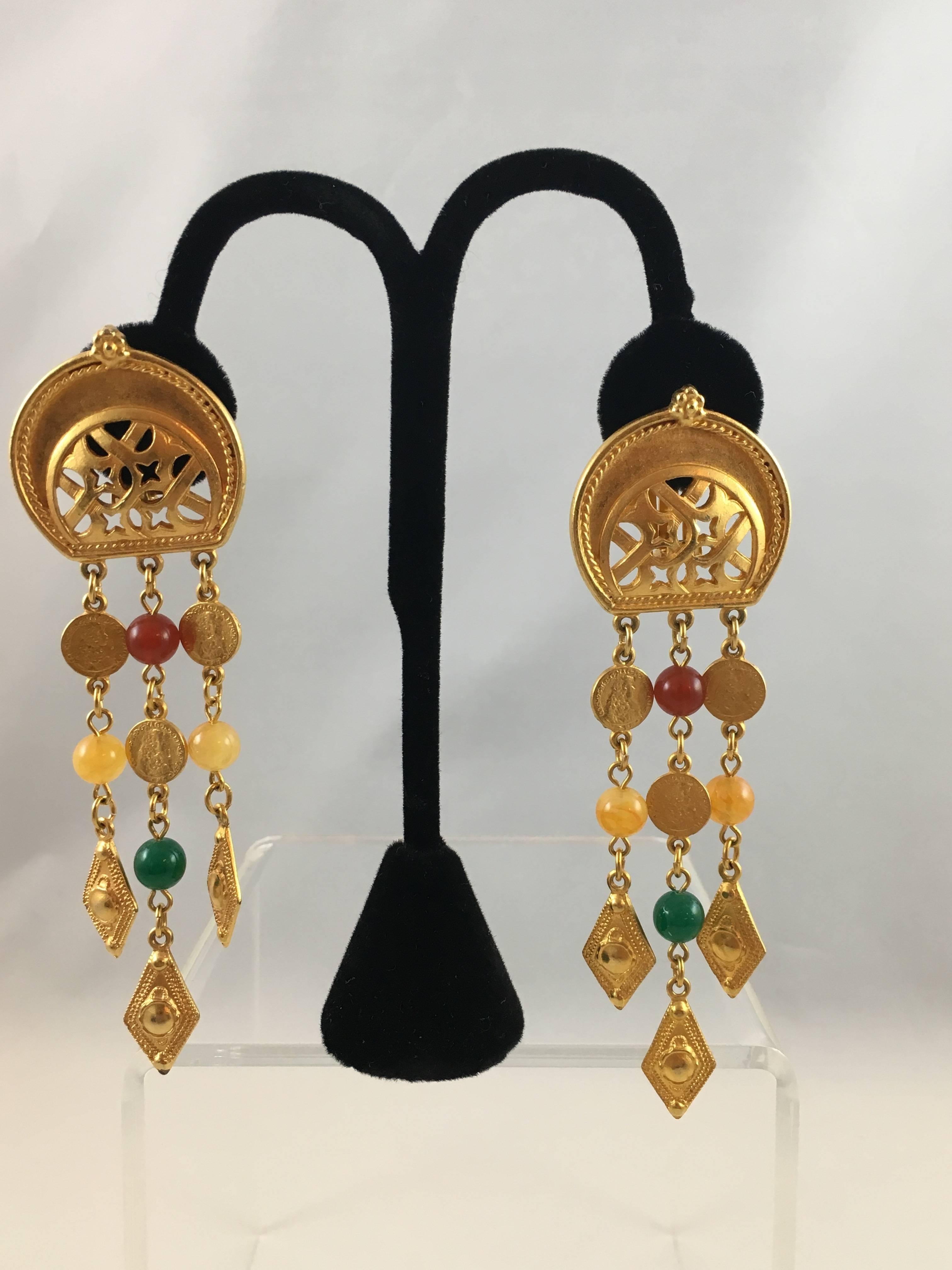 This is a pair of gold-tone Ben Amun clip earrings from the 1980s. Each earring features three chains hanging down with glass stones and faux coins. They are in excellent condition and signed on the back. They measures 4 1/2 inches long x 1 1/4 inch