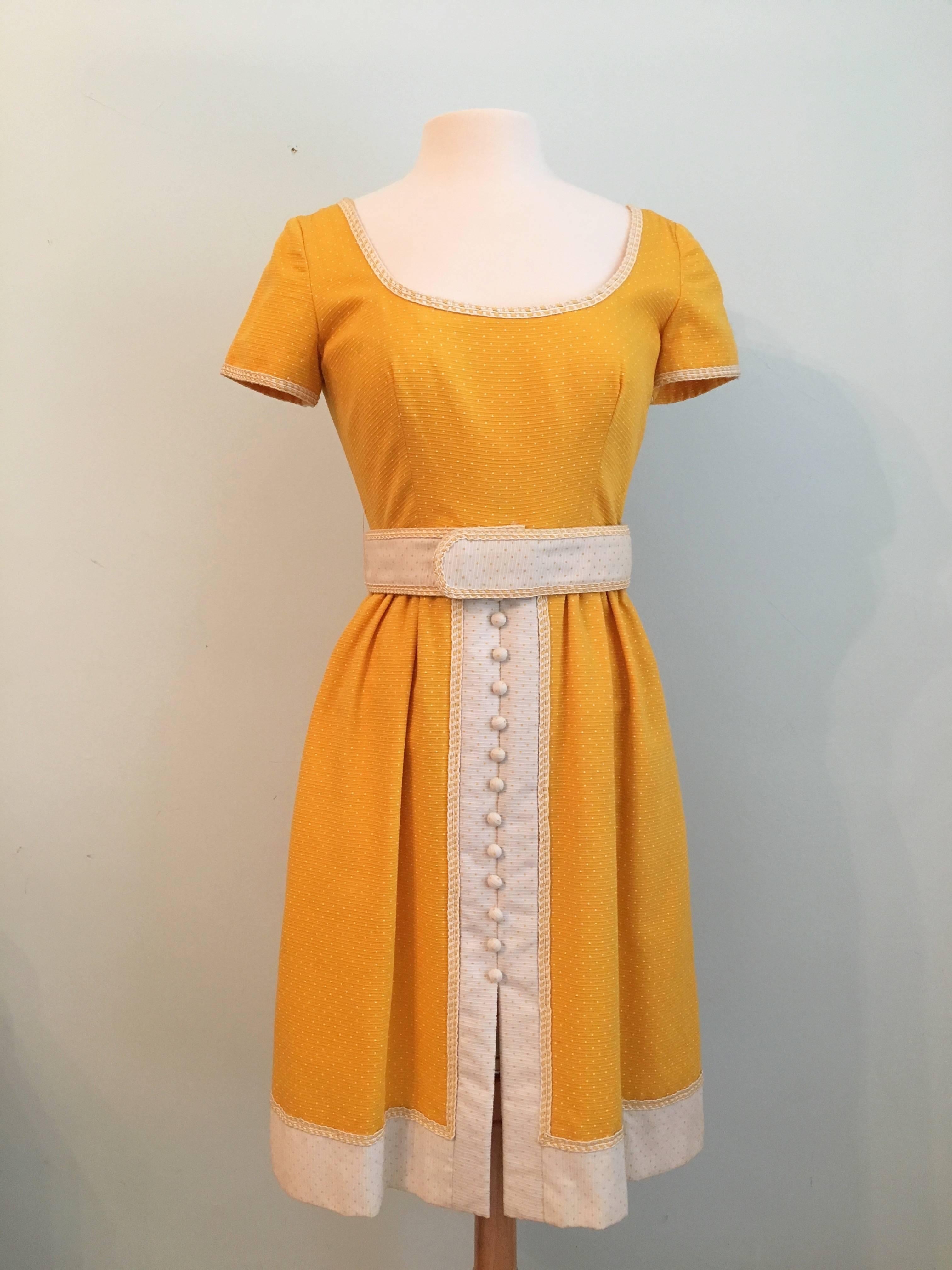 This is a rare 1960s Oscar De La Renta Boutique yellow and white polka dotted dress. The dress is made out of a yellow fabric with a raised rib-like texture that is printed with white polka dots.  It has yellow and white corded trim at the neck and