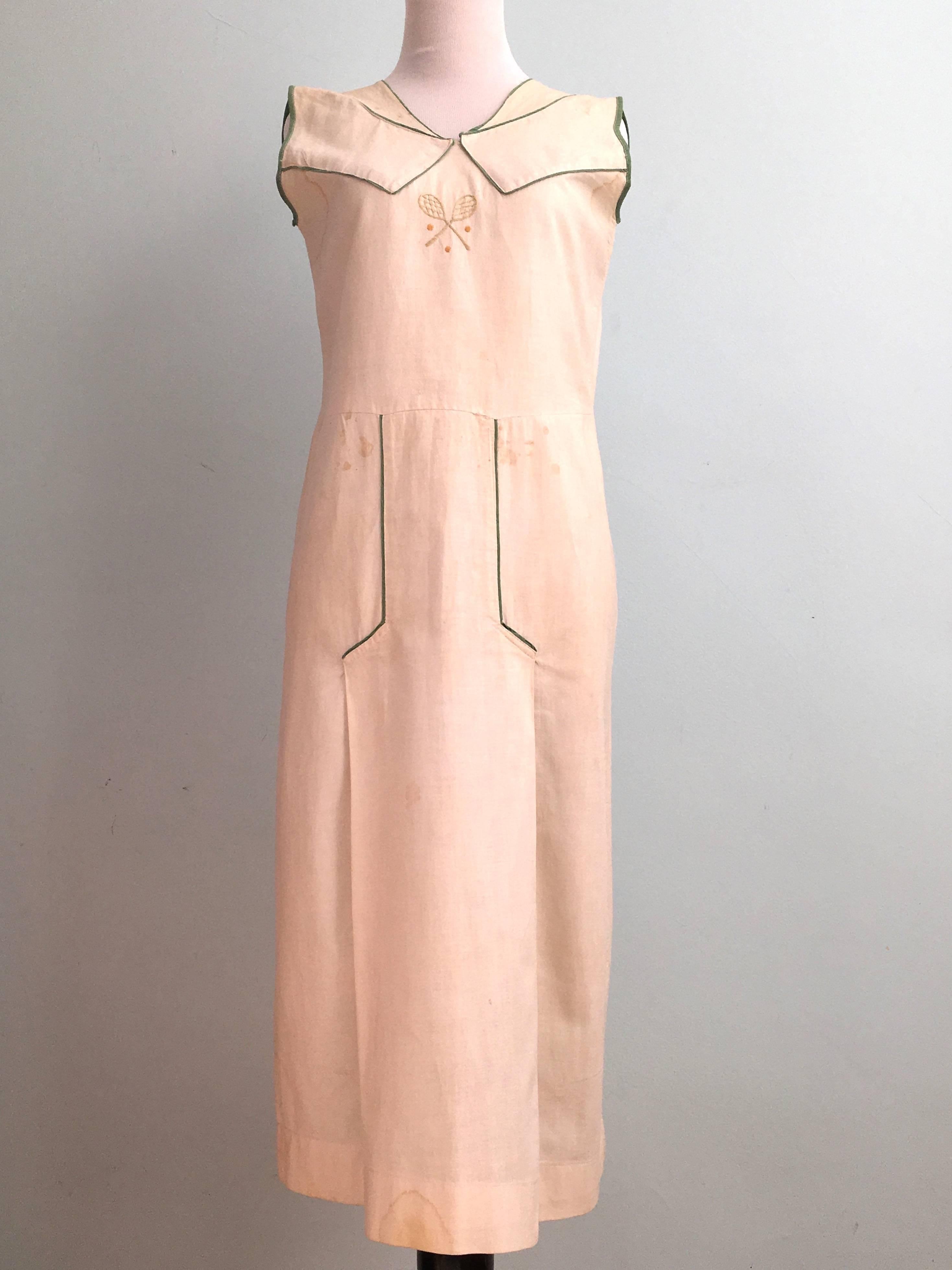 This is a rare tennis dress from the 1920s. Such a fabulous piece! It is made of a white cotton material that is  trimmed with green fabric and embroidered at the center front with two rackets and three balls. The silhouette of the dress is that of