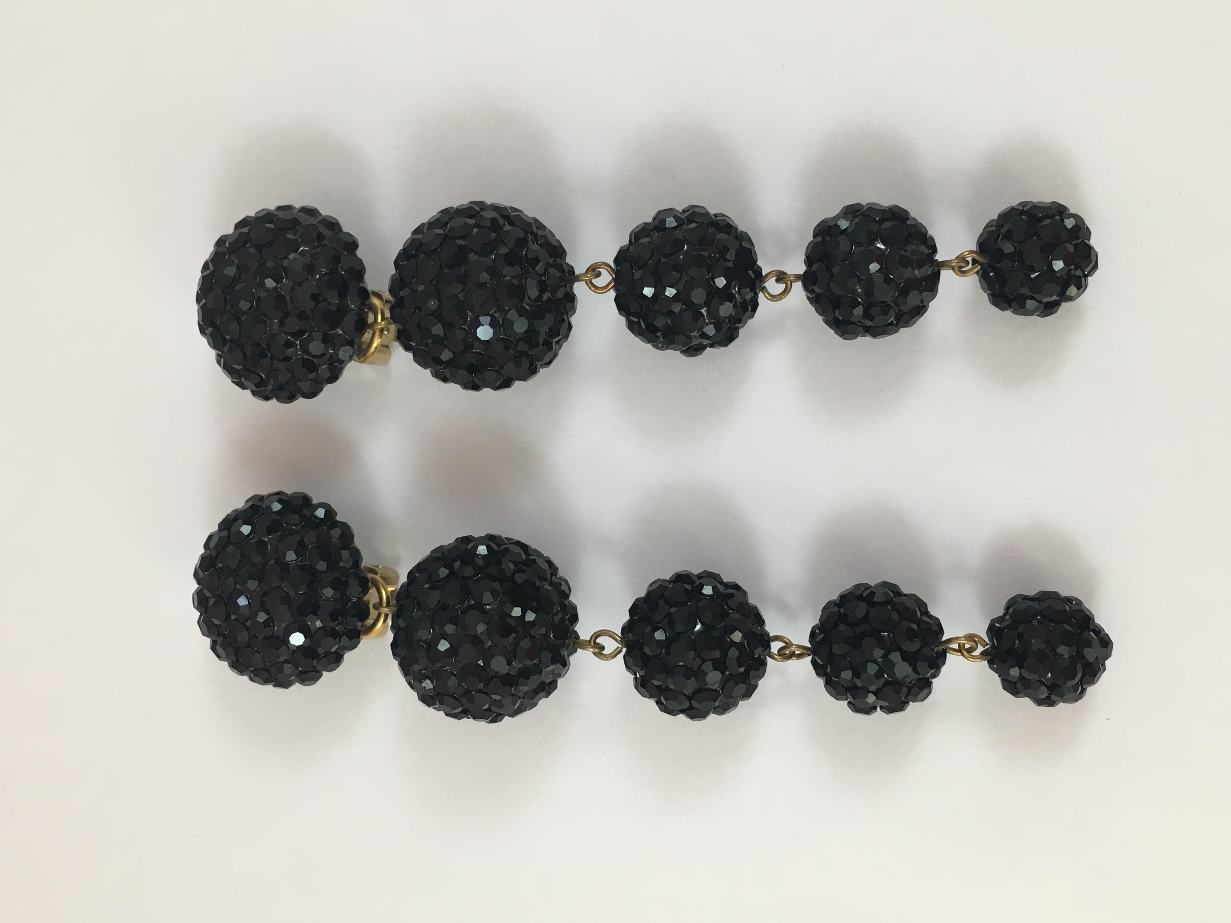 This is a pair of black 1980s Richard Kerr dangle clip-on earrings. They are huge - measuring 4 inches long x 7/8 inches at their widest point. They are made up of five black balls covered in Kerr's signature pave rhinestones. They are marked