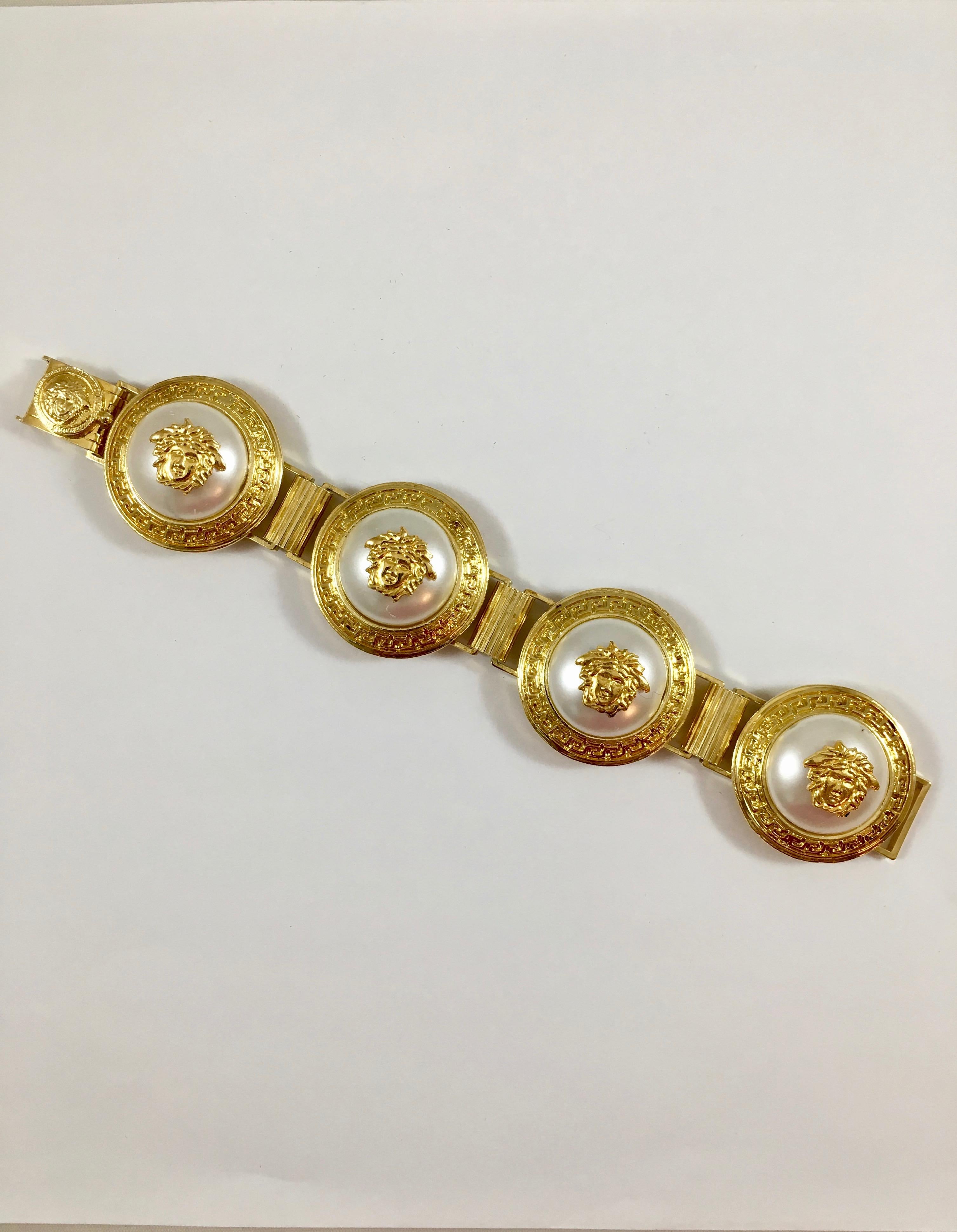 This is a wonderful Versace bracelet featuring four large faux pearl medallions with Medusa heads and gold-tone links. It fastens with a clasp with a Medusa head on it. It is signed in a plaque on the back of the bracelet which reads, 'Gianni