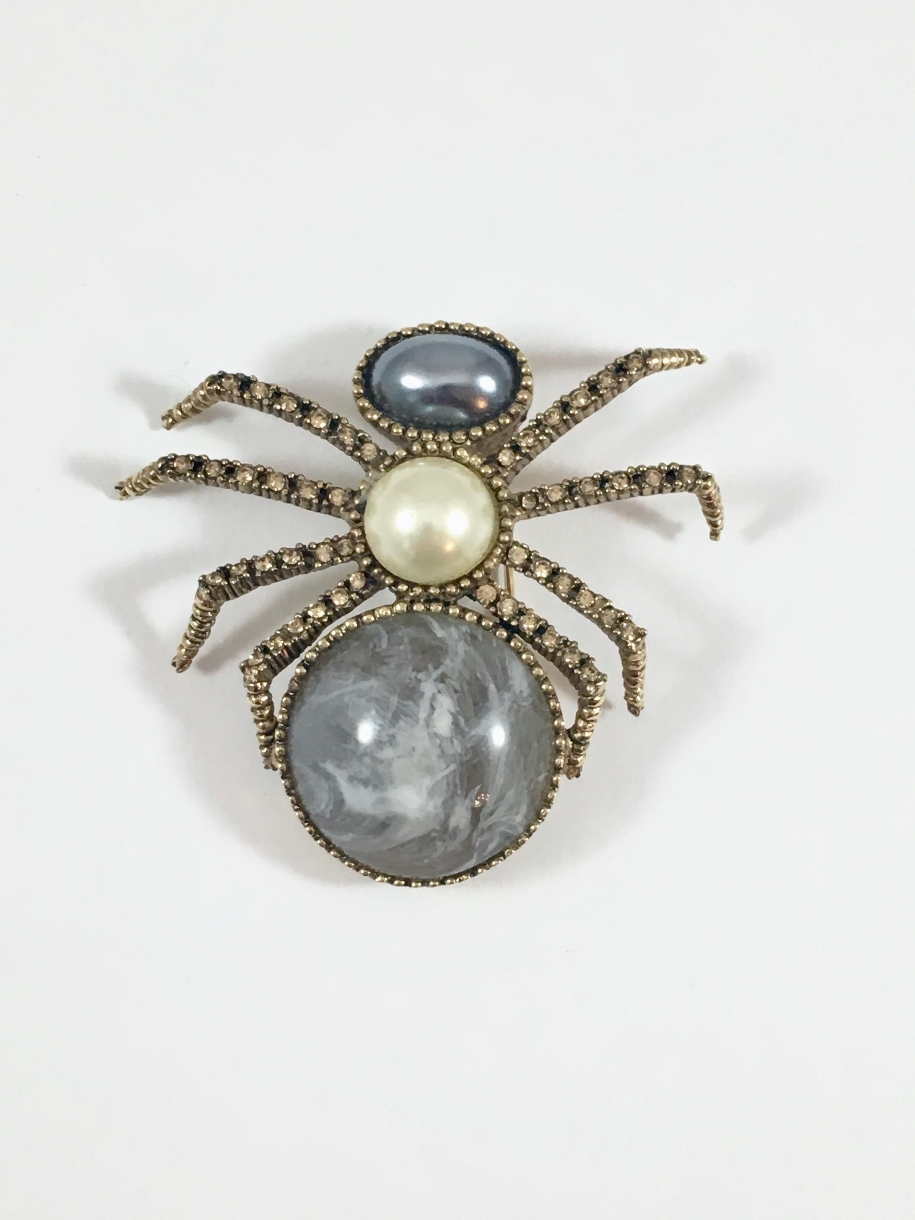 Fabulous Ciner 1970s faux pearl and rhinestone spider brooch. The body is made up of two faux pearls and a gray resin stone. The legs are embedded with rhinestones. It measures 2 1/4 inches long x 2 1/4 inches wide. The back of the brooch is marked