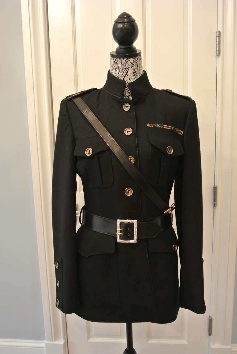 Luca Luca black Nehru blazer with epaulettes. This blazer has an interesting shoulder strap that attaches to the belt with gilt and rhinestone details. Antiqued brass buttons harmonize with metallic thread details.