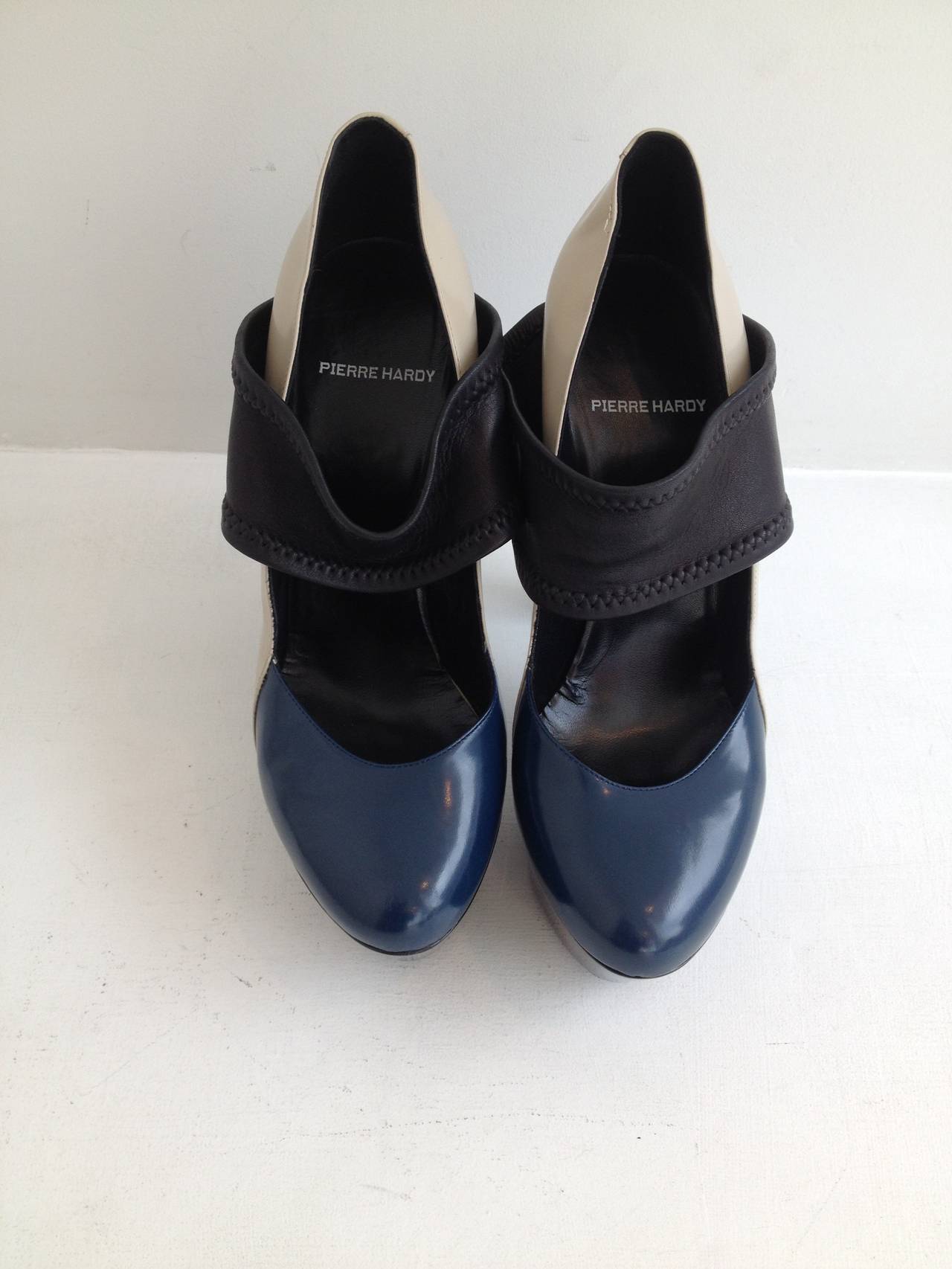 These heels are so wild! The colorblocked body of the shoe features a light French grey heel and sides and a Prussian blue almond toe. The shoe rests on a 1.5 inch platform, in super glossy black plastic, with a towering 6 inch heel in matte steel