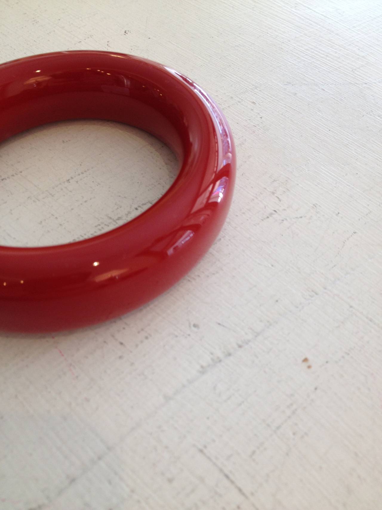 Jewelry designer and model Elsa Peretti uses clean shapes to convey simplicity, graceful design, and modernity. This gorgeous bangle is beautiful in a timeless way - a single smooth-lined ring, made from a deep red material with a glossy, gleaming