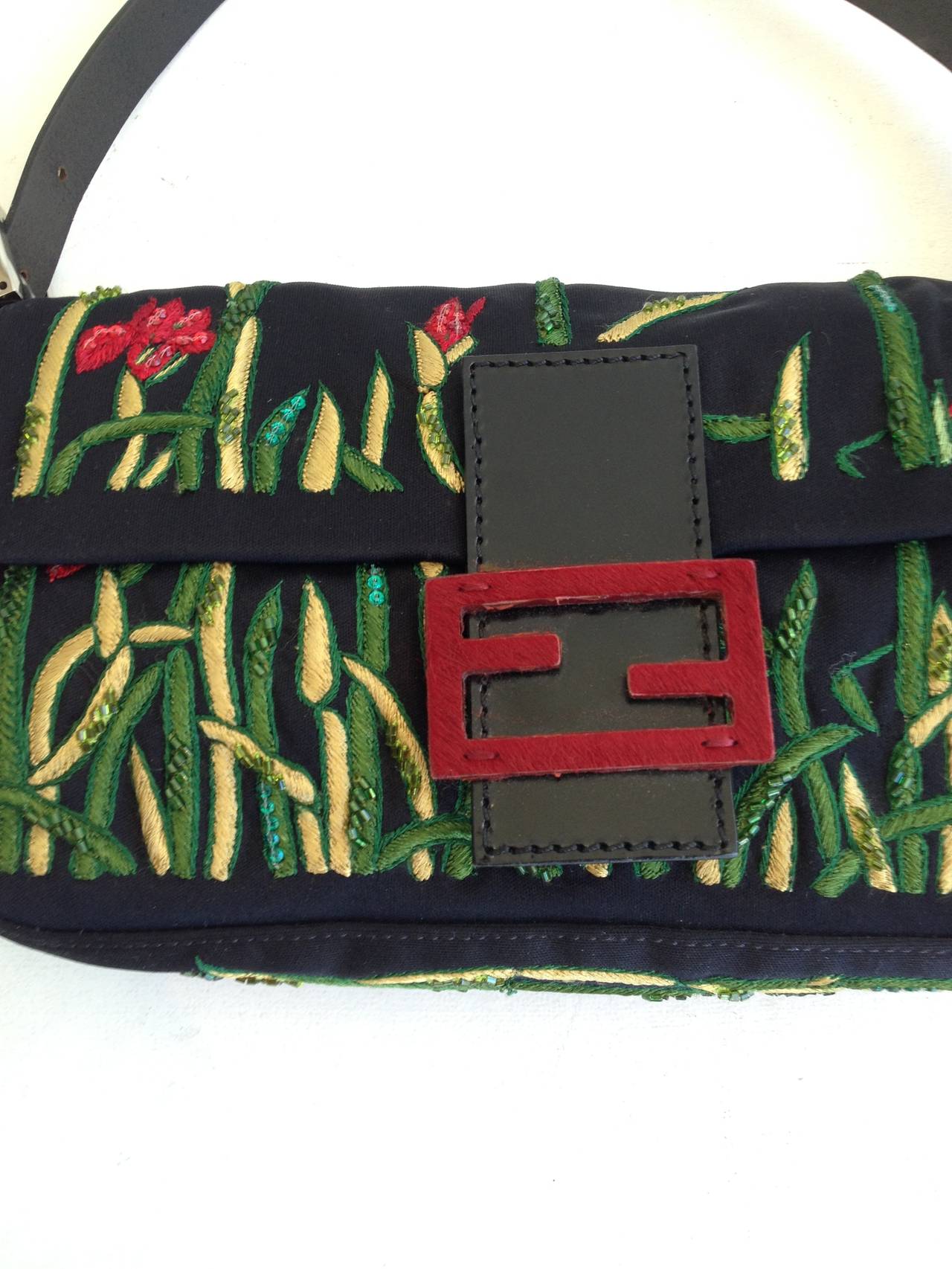 Welcome to the garden of Fendi. Their signature baguette bag is decorated for evening with a dark foliage and flowers - embroidered and sequined spring greens and yellows climb up the sides of the black fabric, with red blossoms to match the red