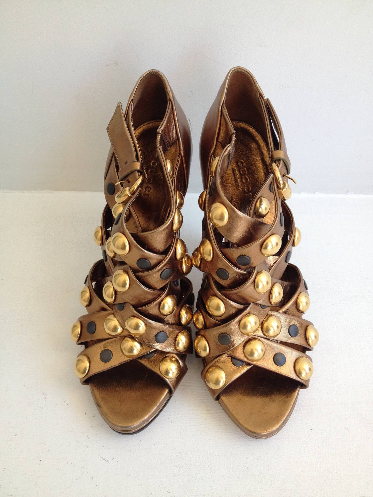 These sandals truly pack a punch! The metallic bronze leather is gleaming, punctuated with a constellation of giant gold semi-spheres and smaller matte black flattened studs. The 4.5 inch heel is made more walkable by the .5 inch platform. These