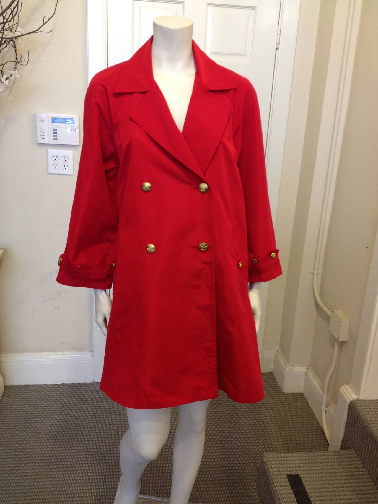 This eyecatching Chanel coat features a beautiful a-line shape for an elegant and feminine fit, and is rendered in a bright carmine red silk twill material.  It's light enough to wear as a duster during the day, while the semi-glossy sheen makes it