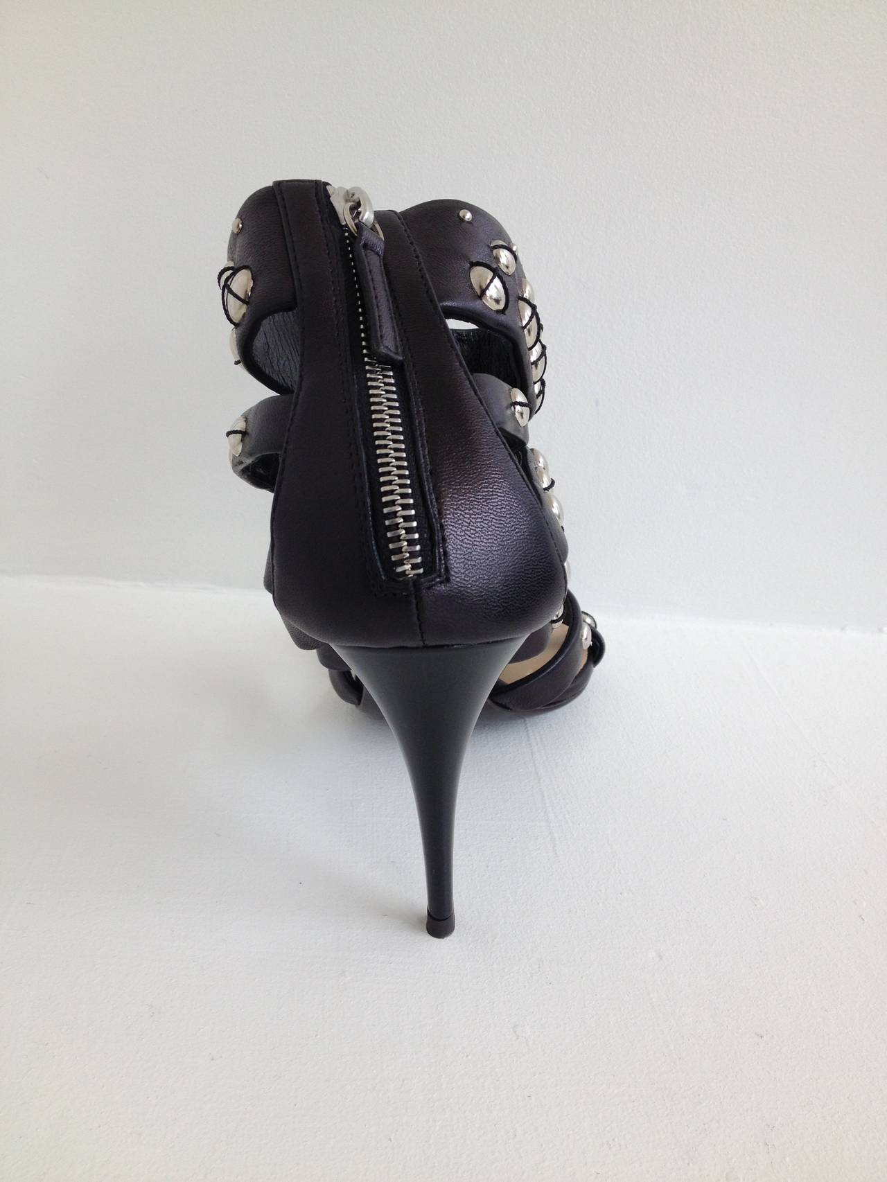 Heavy metal glamour. These Giuseppe Zanotti heels are bold and edgy, with thick black leather straps punctuated with shiny silver round studs, some accented with black leather threads. The 3.75 inch heel is the perfect amount of height. We love the
