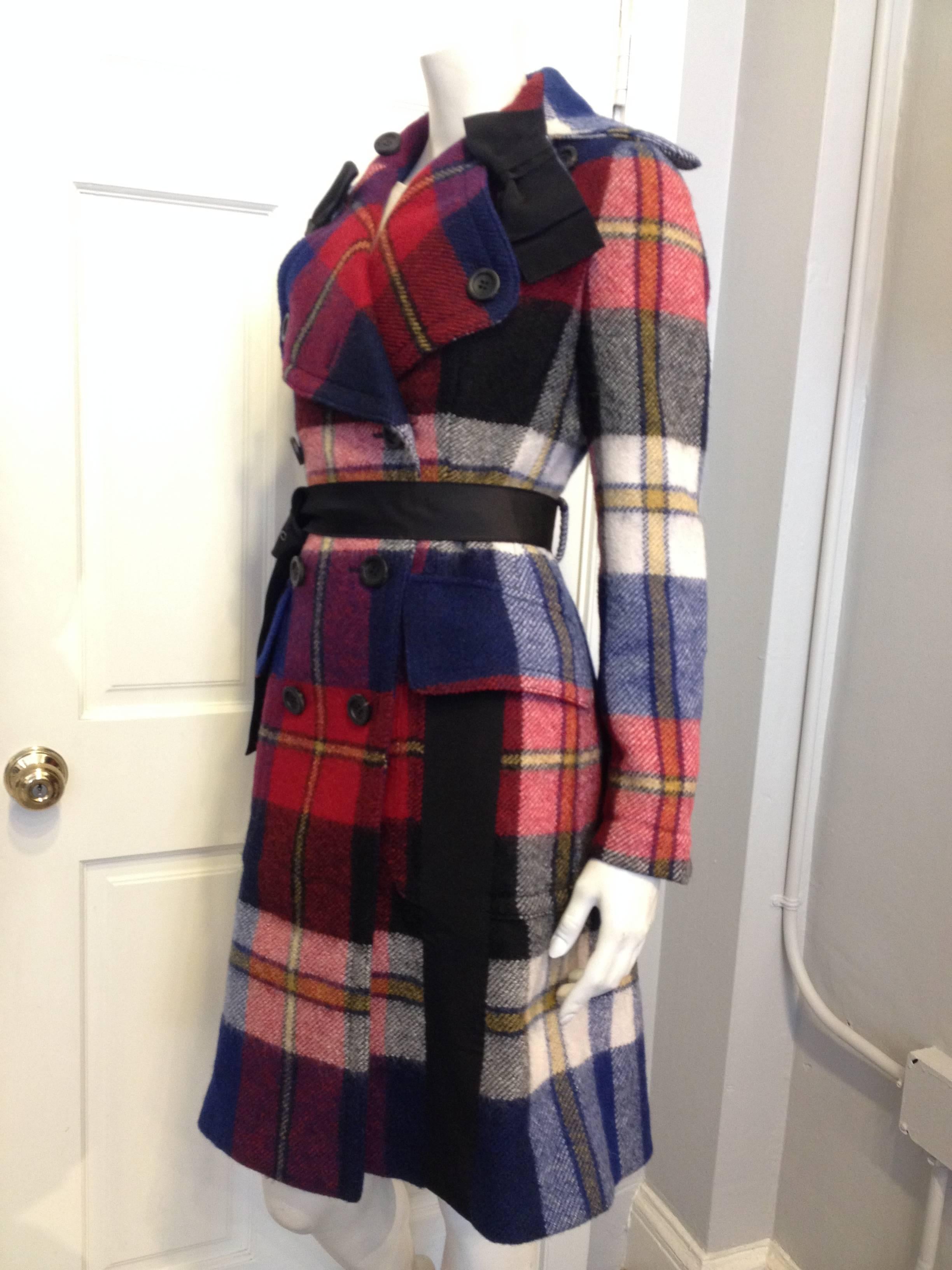 Both chic and ruggedly practical, this coat by Prada takes utilitarian lumberjack wool plaid and dresses it up with big grosgrain ribbon bows. The silhouette is a classic and feminine double breasted pea coat shape, with oversized lapels and pockets