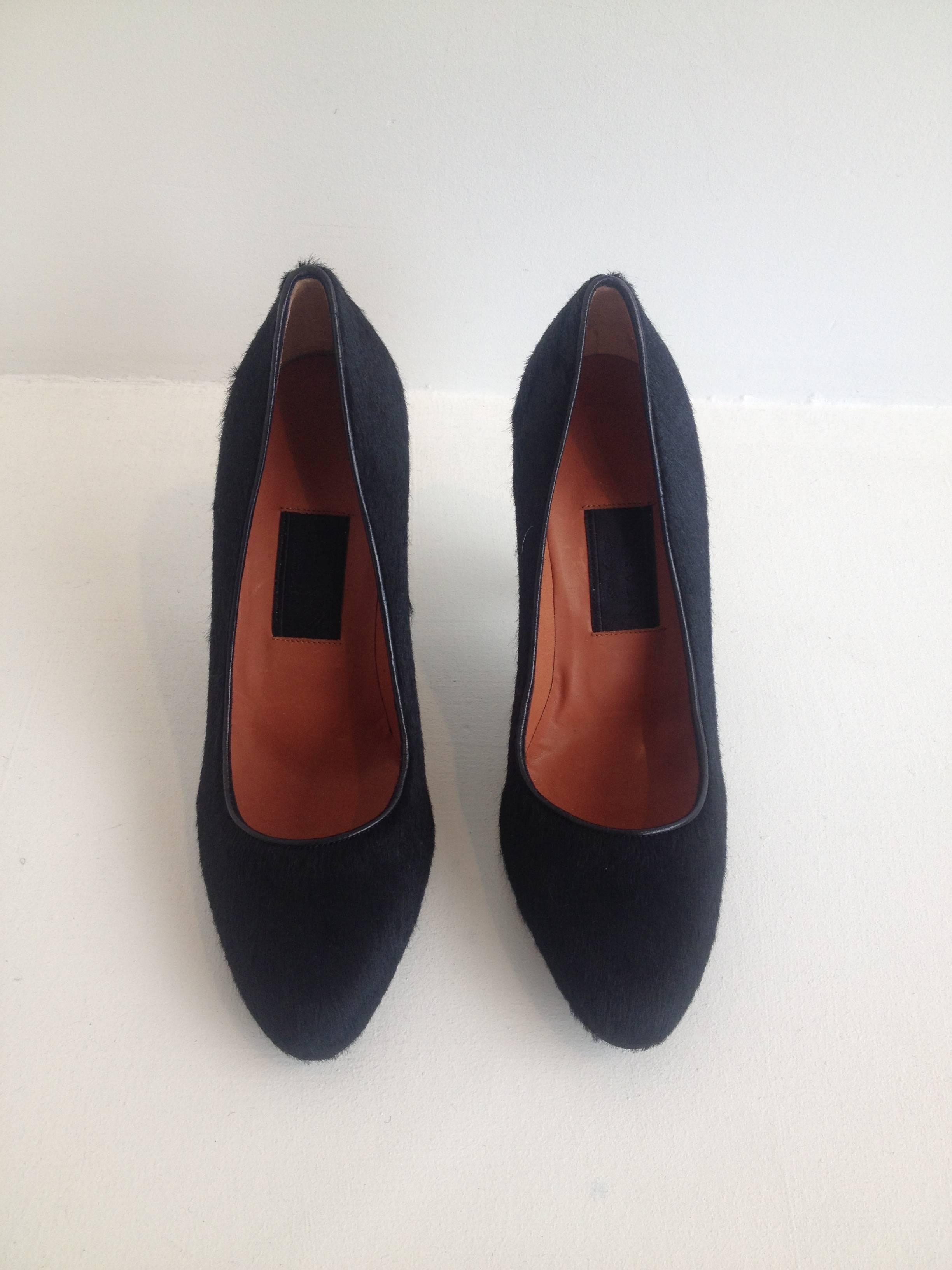 These wonderful shoes are sculptural but very wearable at the same time. It is very intriguing the way Lanvin contrasts colors and textures justopposing the black ponyhair body to the shiny smooth navy 3.75 inch heel. This is a shoe that can be worn