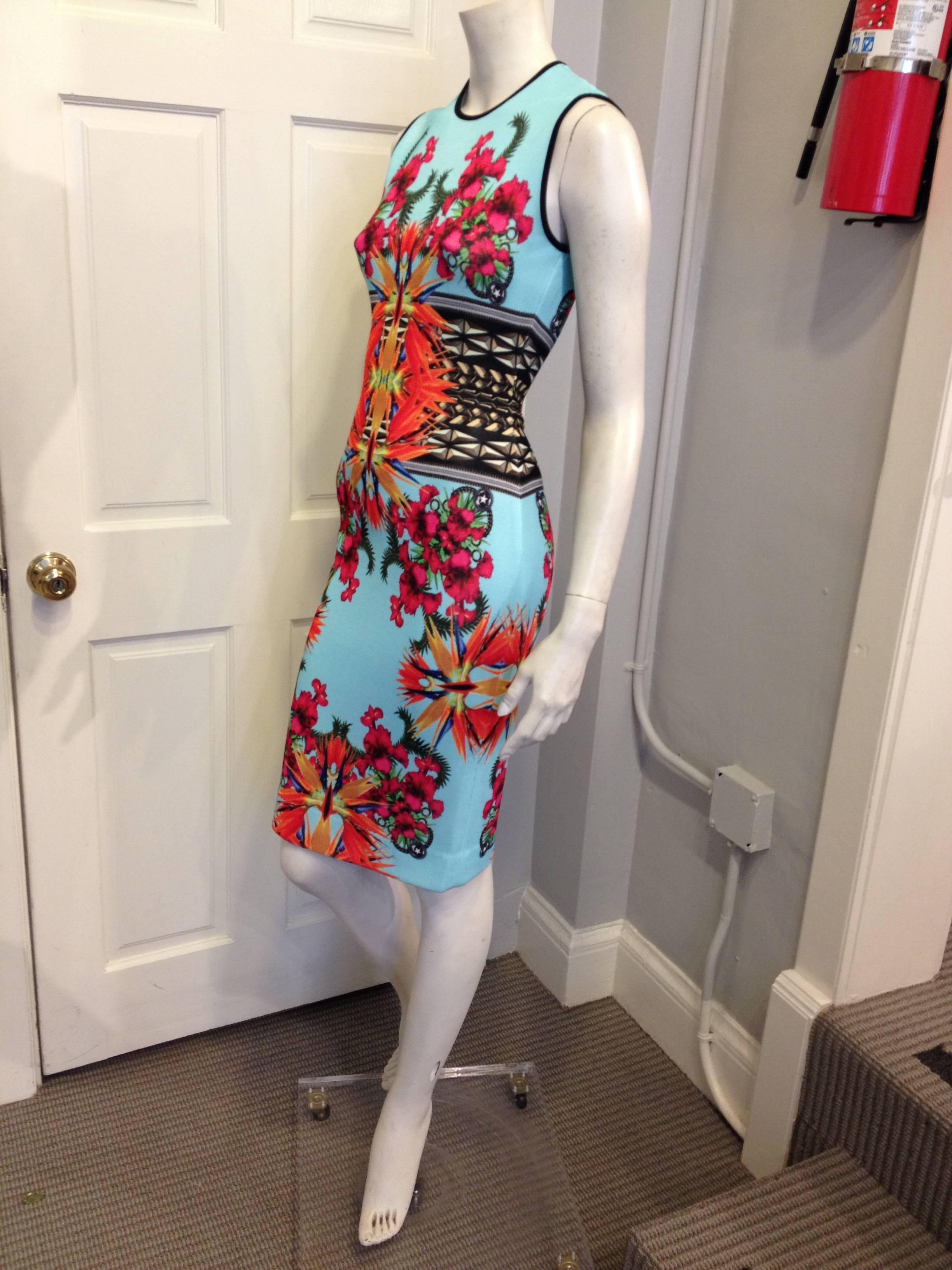 Bright  orange bird of paradise flowers and vibrant fuchsia irises blossom amidst fern fronds, all on a background of aqua the color of Hawaiian ocean water. The tight pique knit and bodycon cut make this piece good for either the day or for a night