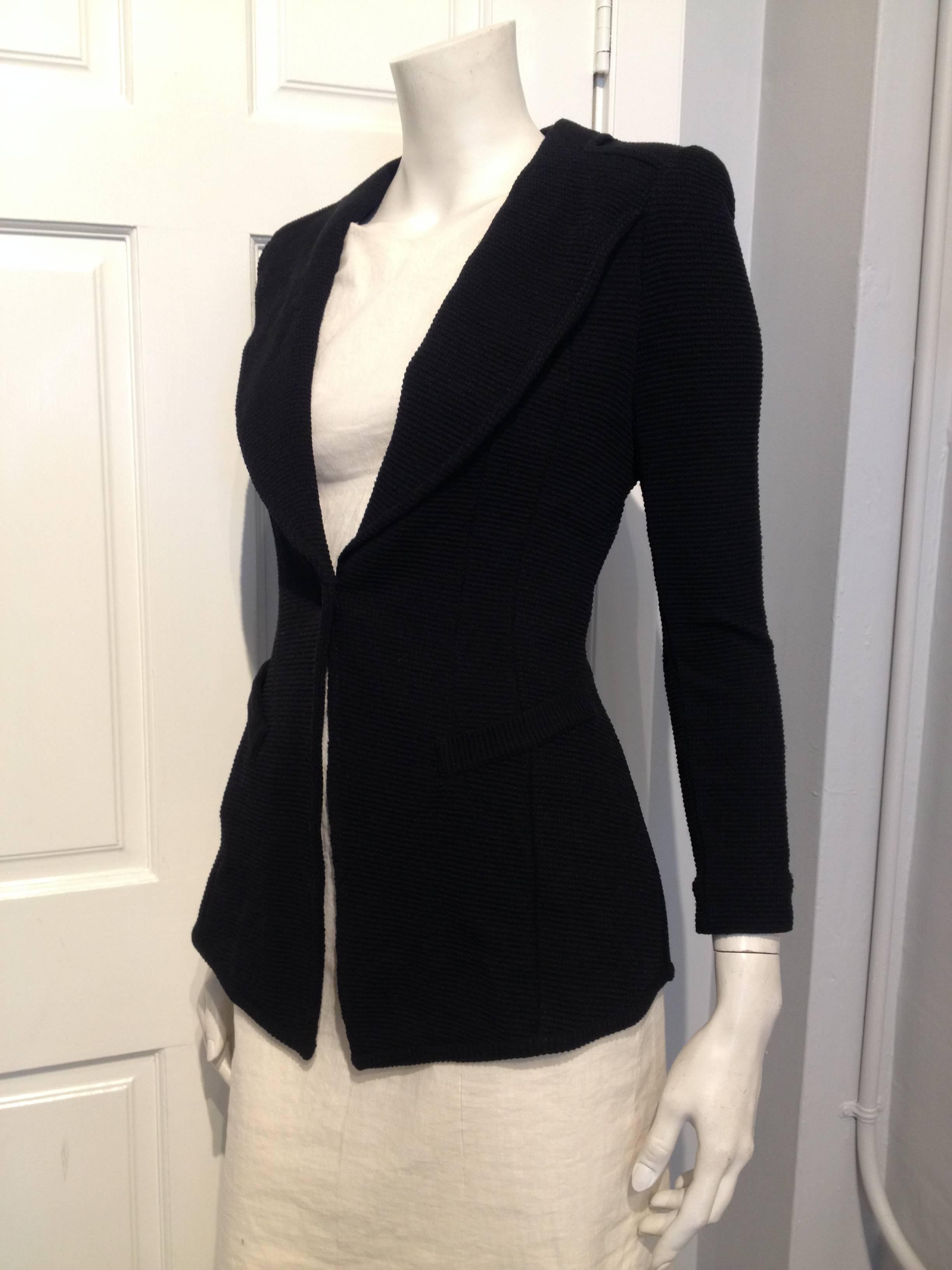 Black knit blazer with lapels connected to the jacket at the padded shoulders, very slim cut, long sleeves, single button closure, and open vent in the back.