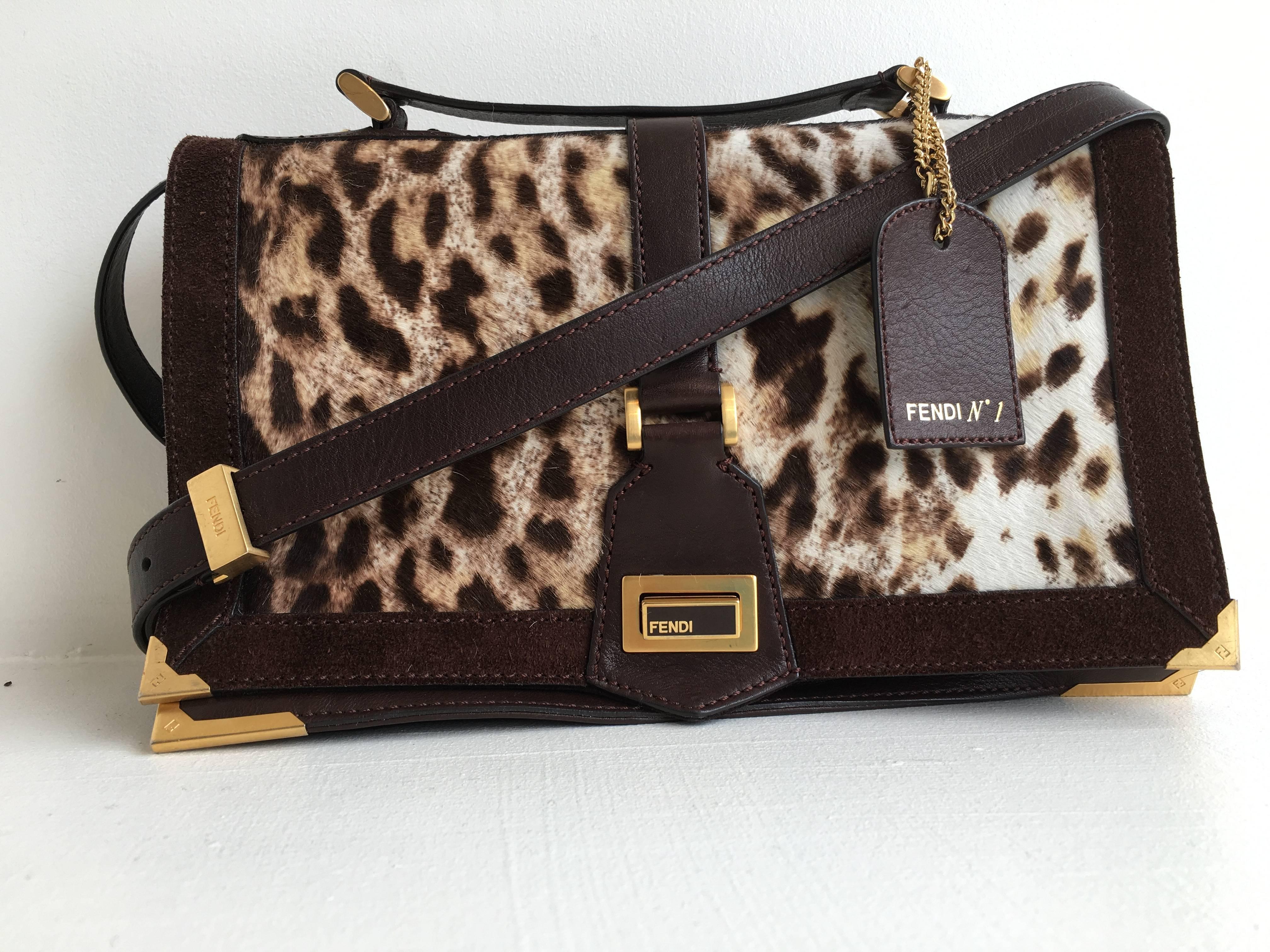Fendi No.1 crossbody bag in leopard print haircalf with brown leather siding and brown suede border. Each corner is sealed with gold tone metal engraved with the double F logo.
The inside of the bag features two fabric lined main compartments, with