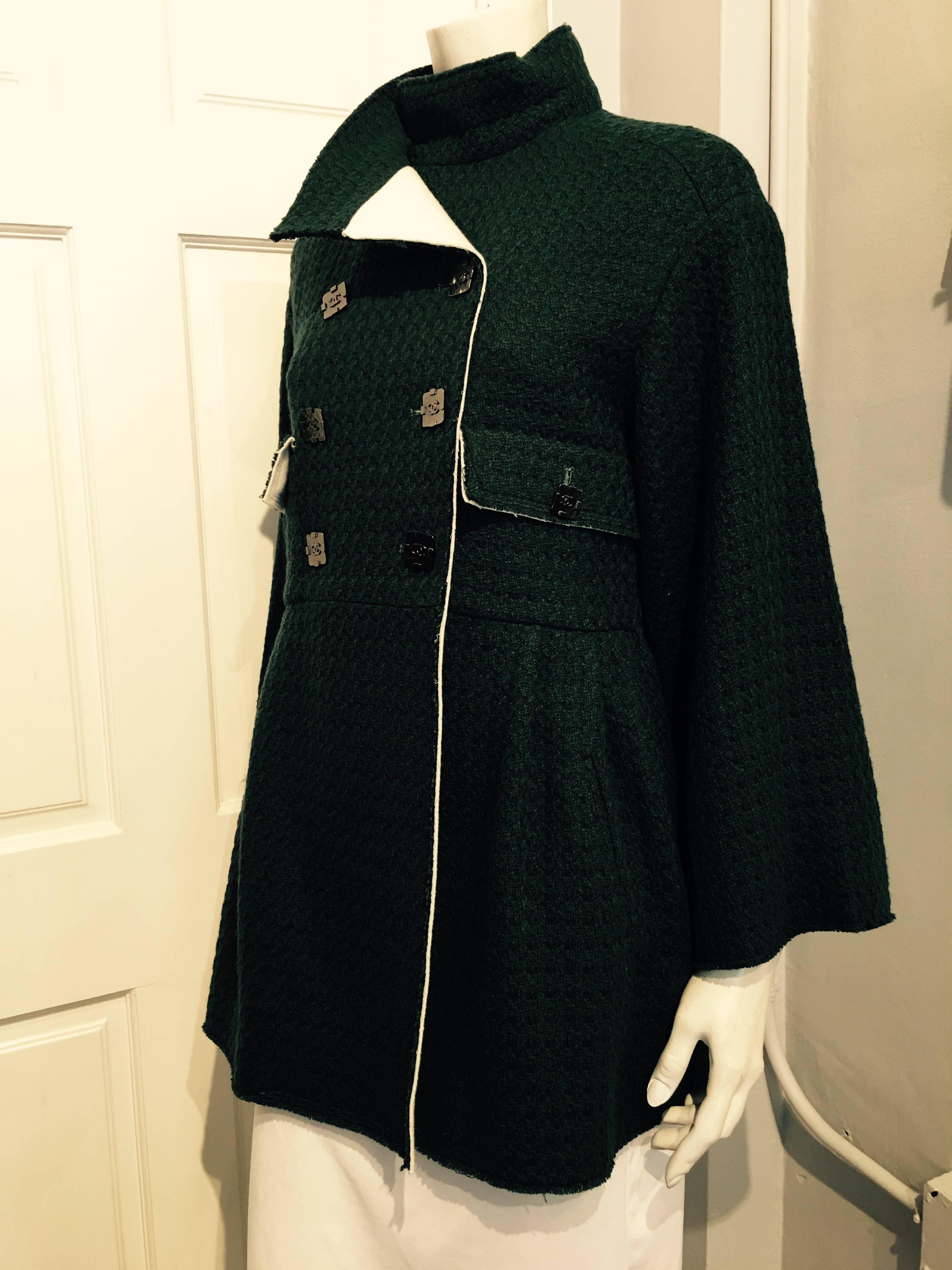 Chanel 3/4 length green tweed jacket in a houndstooth weave. The garment closes with a double row of square gunmetal color buttons with iconic CC and with two more smaller buttons on the flaps of two pockets at the waist. The skirt of the jacket has