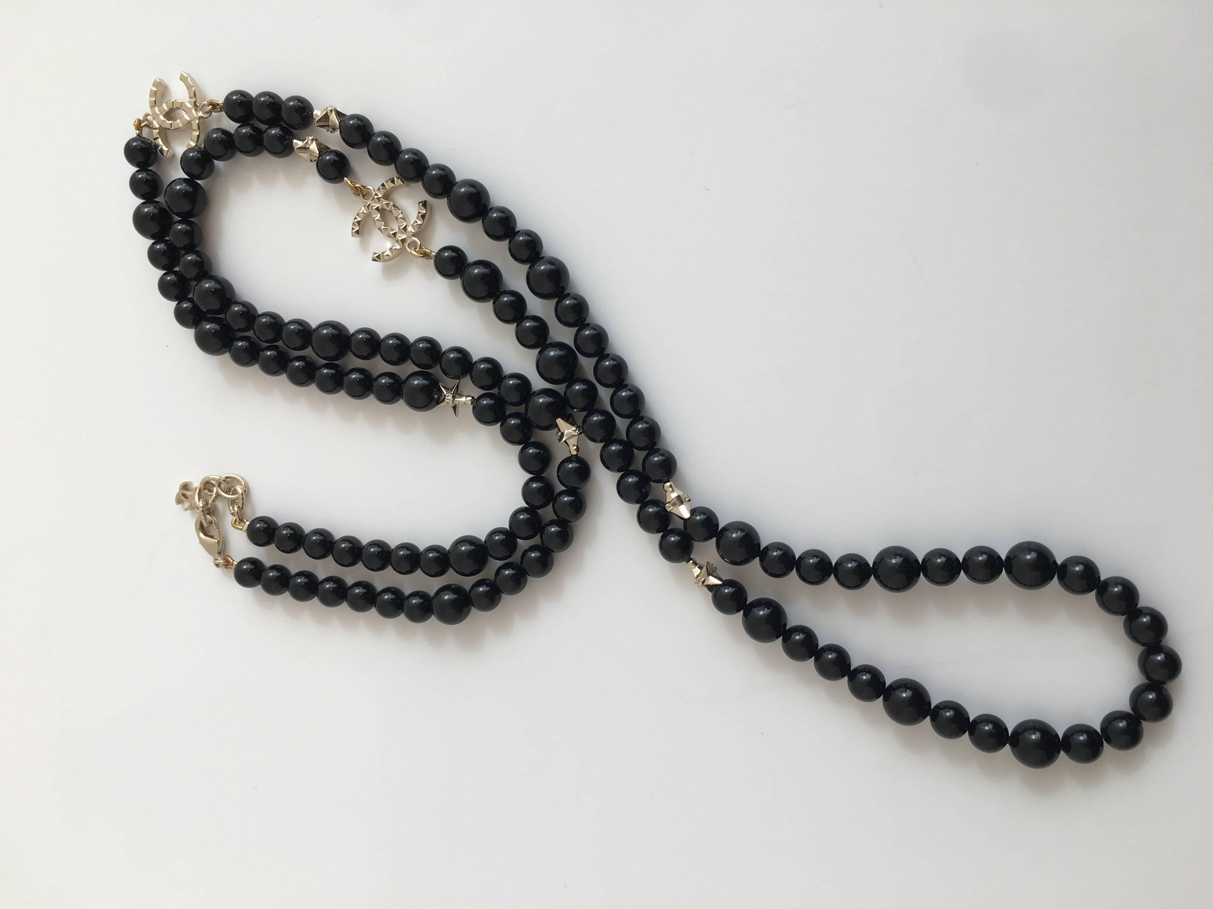 Chanel single strand black beaded necklace with two CC charms and six smaller star shaped beads. The CC and star beads are a muted gold color metal.

The necklace comes in a soft Chanel case.