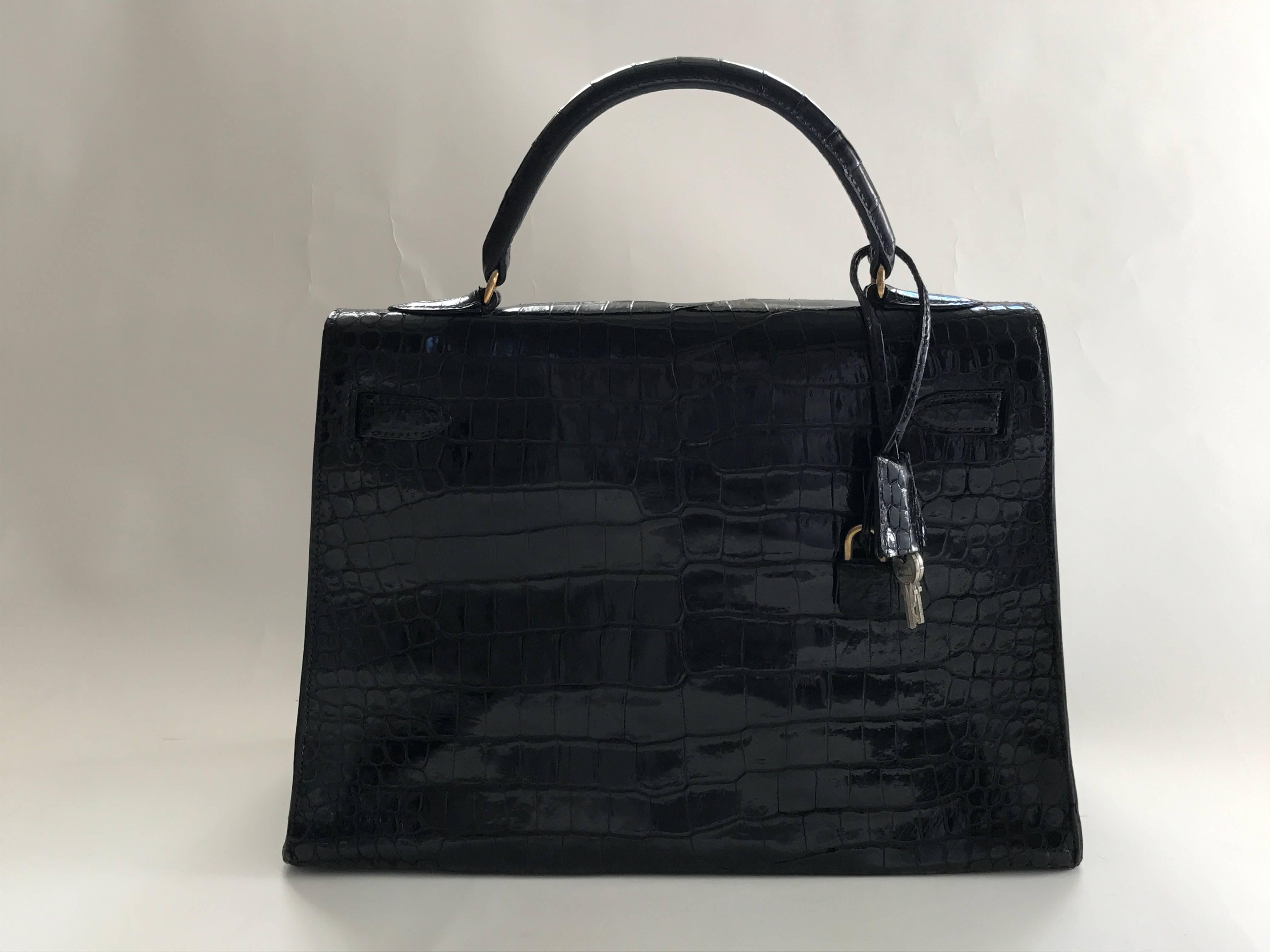 Black vintage Hèrmes Kelly 32 with gold plated hardware. Single top handle. The lining is in black chèvre leather with one large wall pocket and two smaller ones. The bag comes with box, dust bags, lock and two keys, and the original comb in a croc