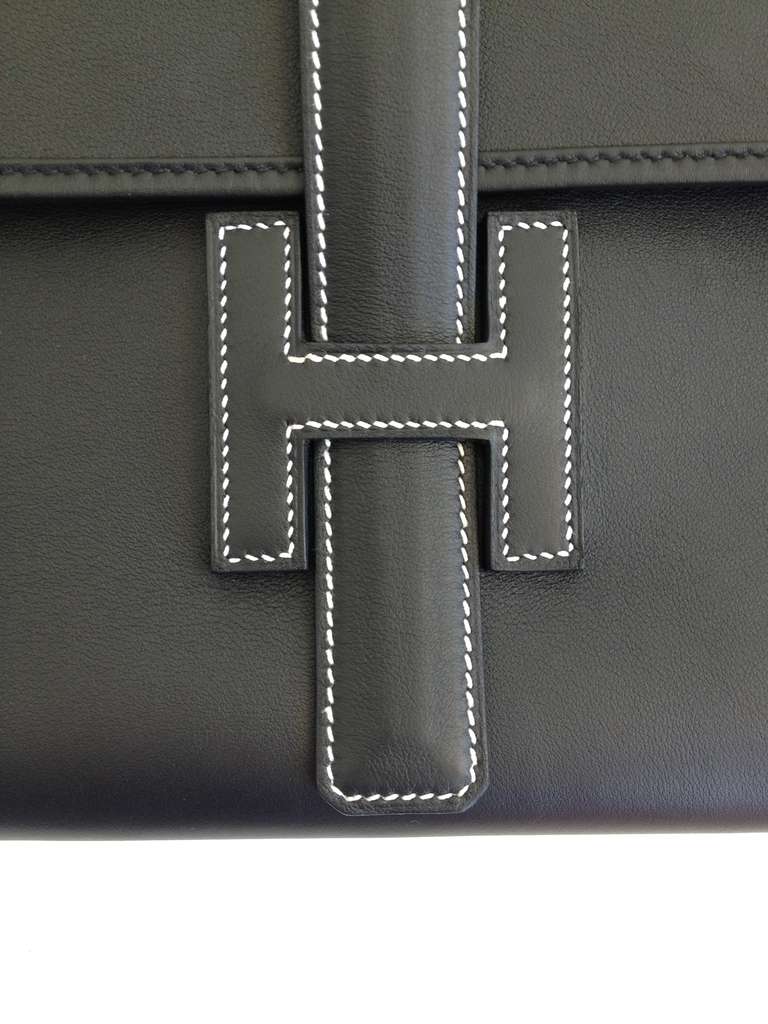 This is the must have item for all Hermes lovers.  Exquisite black leather makes this the perfect clutch to carry for any occasion.  The interior is lined in beige fabric and the front flap closes with the strap sliding through the 