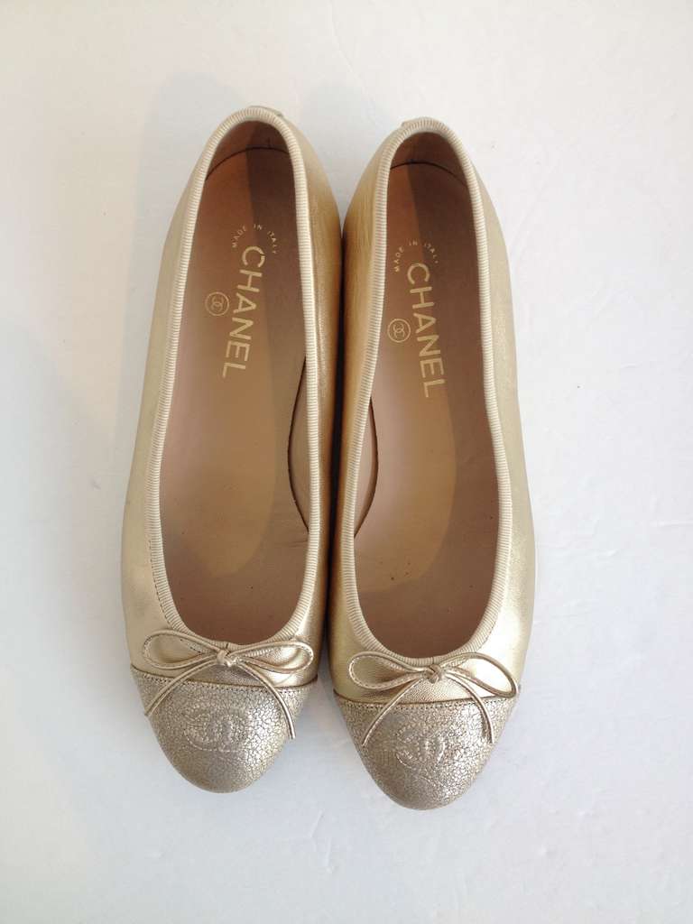 Chanel's classic flat in a shimmering gold leather with a crackled gold leather cap toe.  A raised CC logo can be seen on the toe and the piece is finished with a perfect gold leather bow.  The perfect ballerina flat, it is comfortable and
