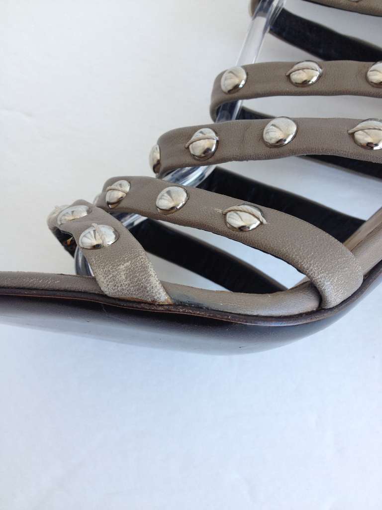 Add a little edge to your day with these strappy leather sandals.  Neutral, taupe leaher is studded with varying sized round, silver studs.  Alternating studs have a piece of thread on top as an added detail.  This 4 inch heel makes a statement