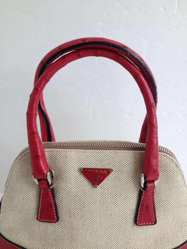 This Prada packs a lot of punch for such a tiny bag! With a creamy canvas body and red ostrich accents, this bag is the perfect miniature purse. Ideal for when you just want the essentials, it has both a short set of handles that rise 3.5 inches