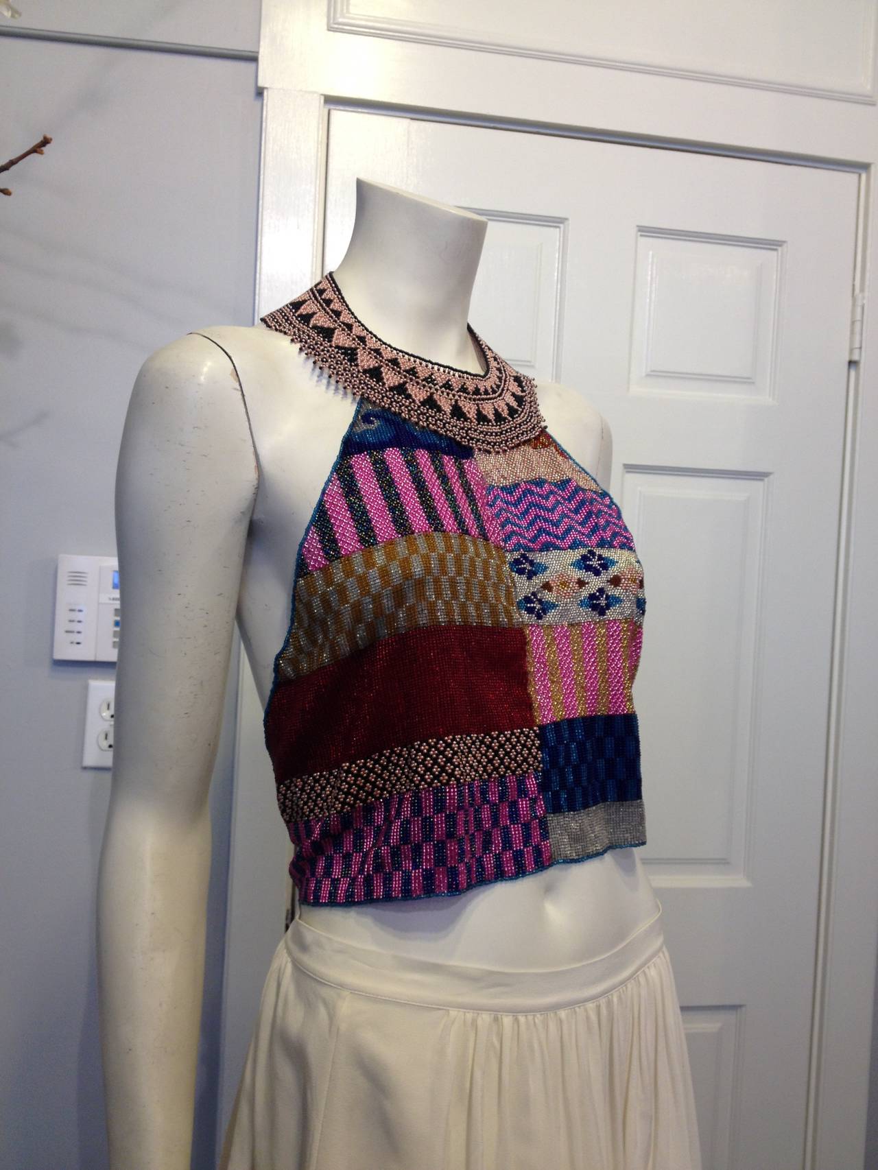 This wild  halter top is a patchwork of a gorgeous and intricate hand-beaded materials, woven in a boldly colorful pastiche of patterns. The elaborate neckline fastens at the back like a collar, while the triangle-shaped body of the piece wraps and