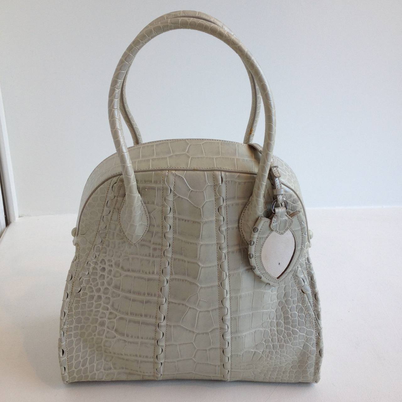 This piece by Azzedine Alaia certainly makes a statement - in gorgeous reptile embossed leather, it's a timelessly luxurious piece. Two curved handles rise above the top of the bag, while the shape is compact but spacious. The interior is lined in