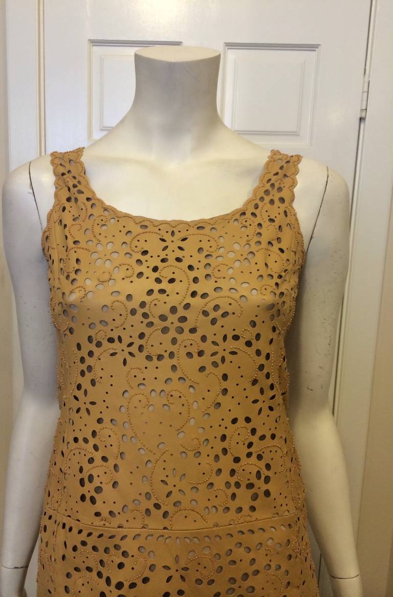 This Oscar de la Renta piece is sure to turn heads. What initially looks like sequins are actually little round cutouts sprinkled all over the body of this piece, which is also decorated with little brown lines of beading. The dress itself is made