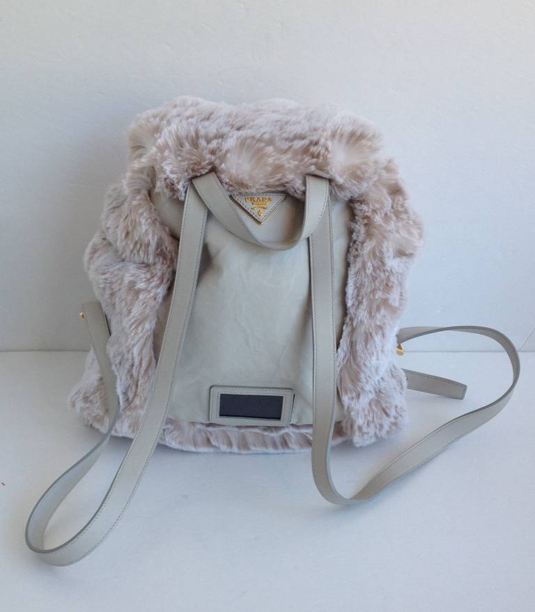 This backpack has a lot of personality! Super soft dusty taupe faux fur covers the outside of the pack and the flap top, which fastens with gold hardware. The straps, handle, and back part of the bag are made of soft, cream leather. Youthful and