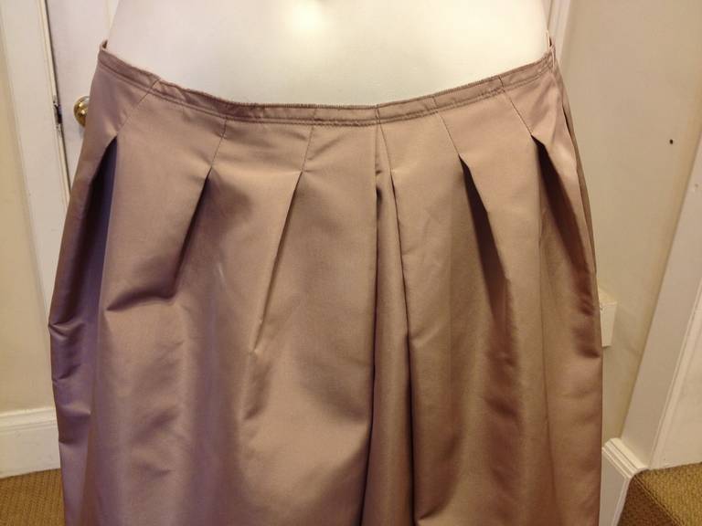 In a soft, subtle mauve-tinted beige, this skirt is beautiful! The slim waistband is perfect for tucking a loose silk blouse into, while the puffy pleats at the front create a gently full shape. The hem is studded with a grid of beaded flowers,