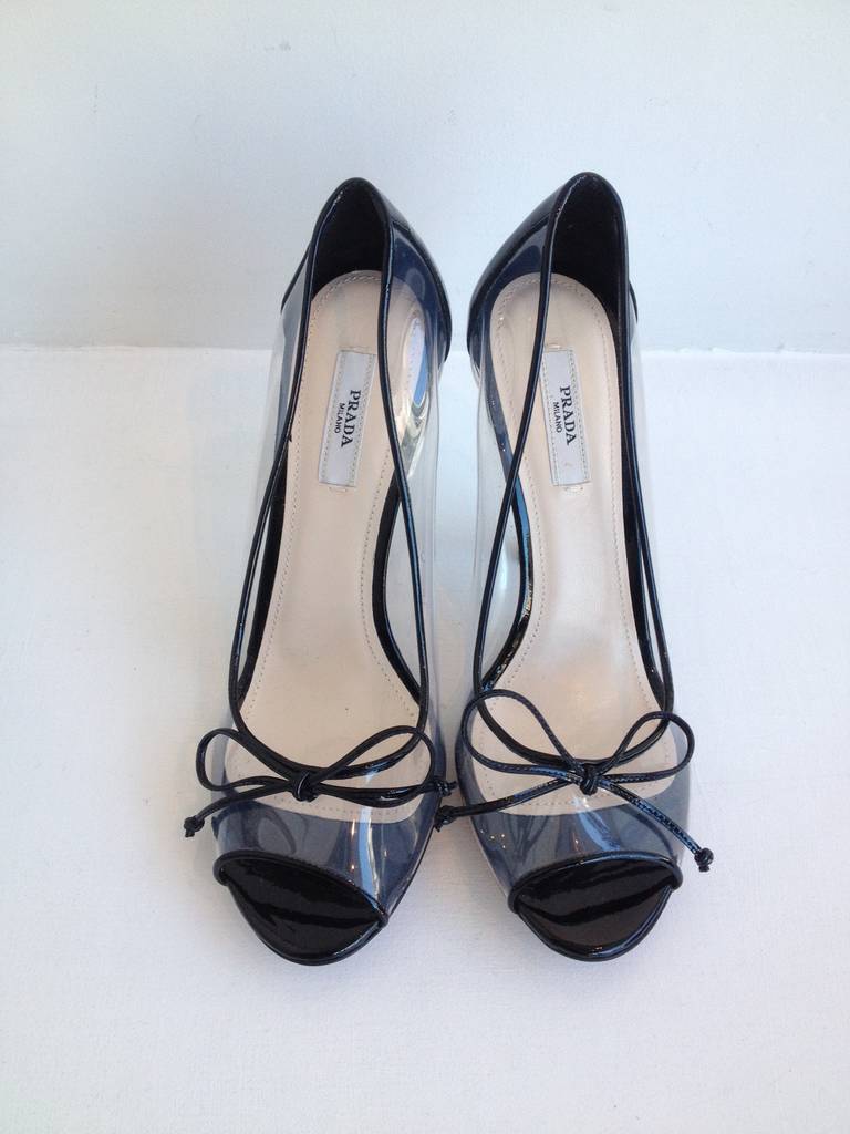 Modern Cinderella would love these shoes! The clear vinyl material and shiny black patent create a sleek, futuristic look, while the bow, black piping, and the open toe keep it feminine and pretty. Wear with a pleated full skirt and a cropped tank