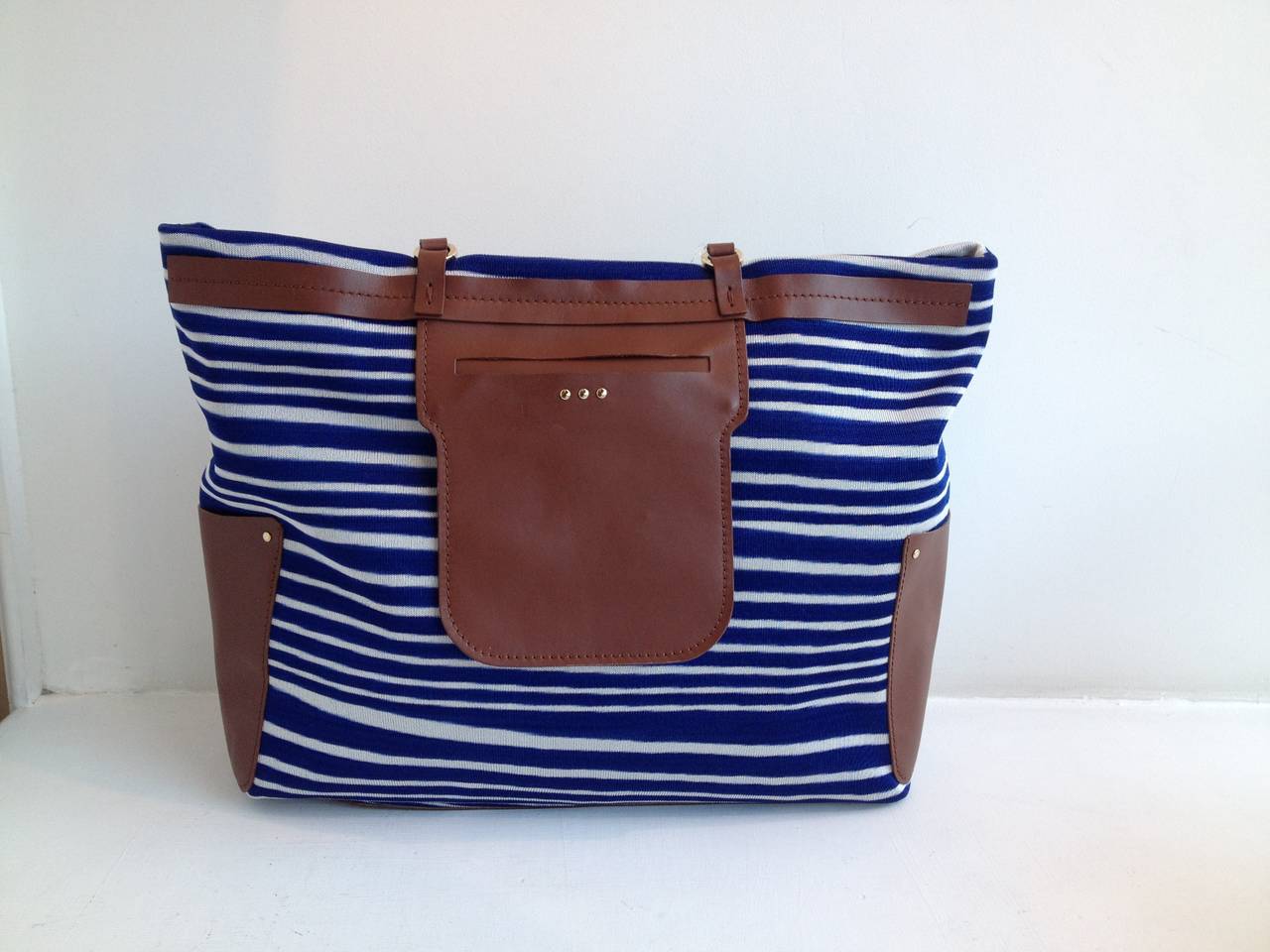 We're seeing stripes! This fun Missoni bag has a standout, cheerful look - the bright blue and white stripes draw from classic Missoni knit patterns, while the brown leather trim adds contrast. The bag features two studded handles with an 8.5 inch
