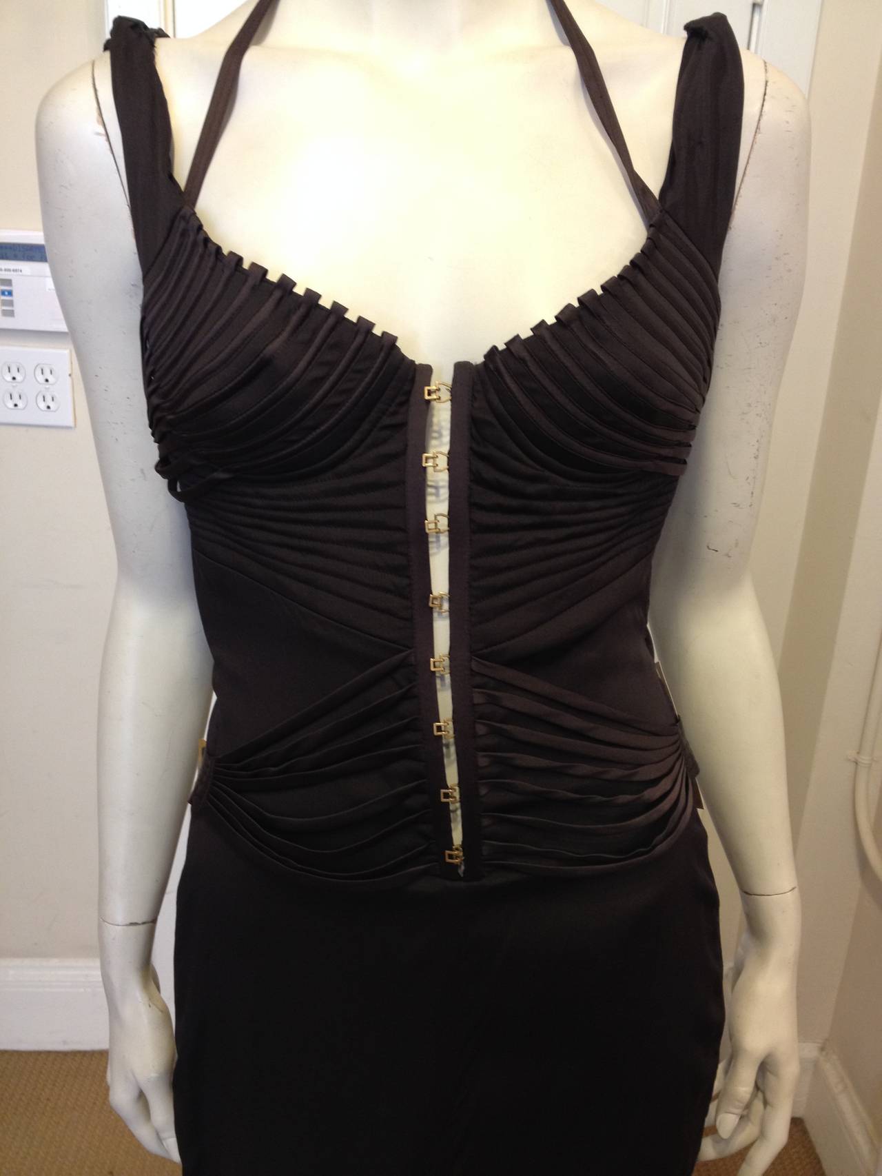 In a dark, rich brown silk, this dress is truly amazing . The structured bustier-style top is decorated with brown silk-covered ribs, which run in concentric lines across the bust, torso, and back and can be adjusted with little gold buckles. The