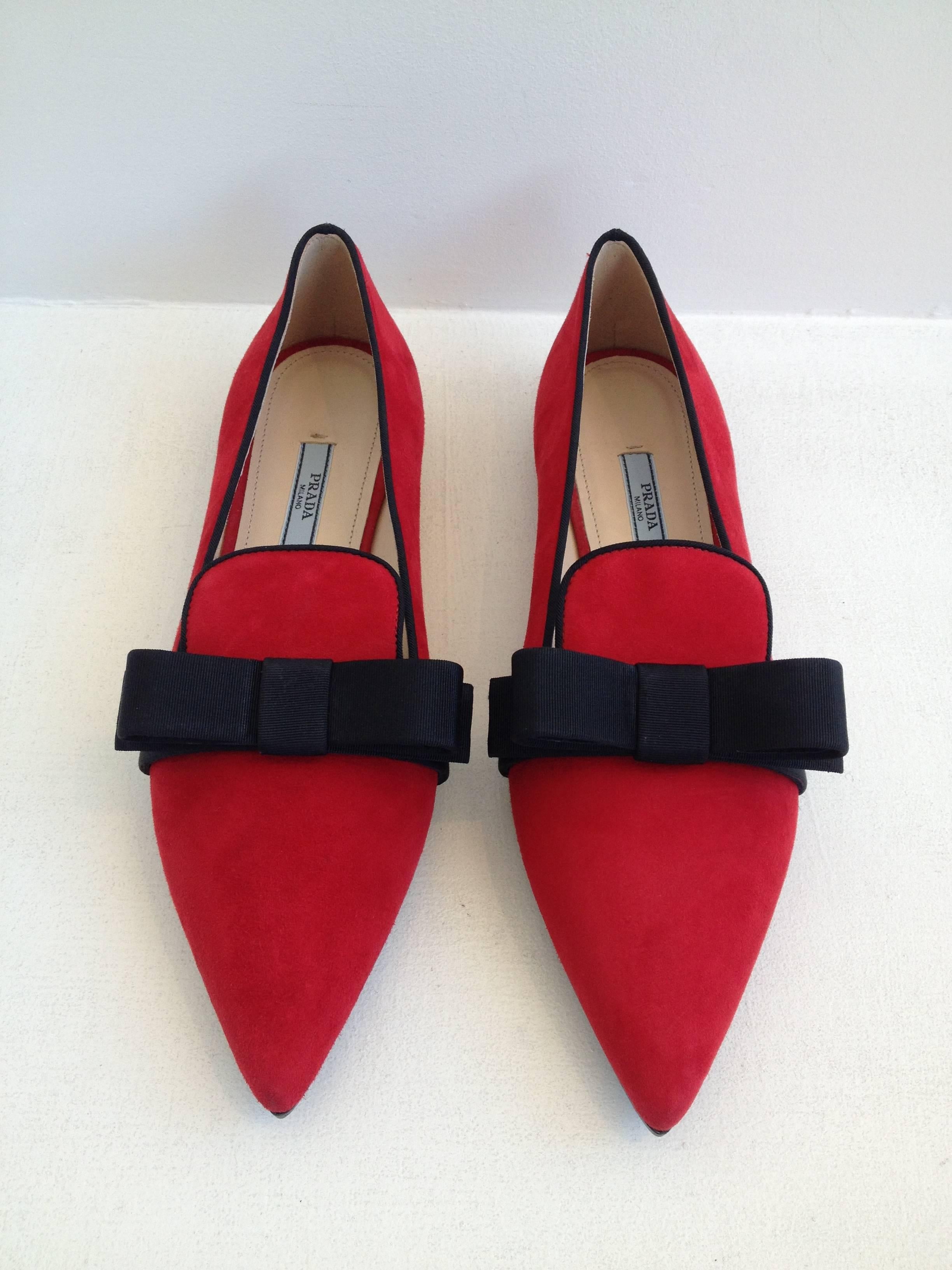 Nothing adds quite so much fun to your look as a pair of red suede smoking shoes. These are trimmed with oversized black grosgrain bows on each pointy toe, adding the perfect contrast to the red. Wear with anything from a party dress to black pants