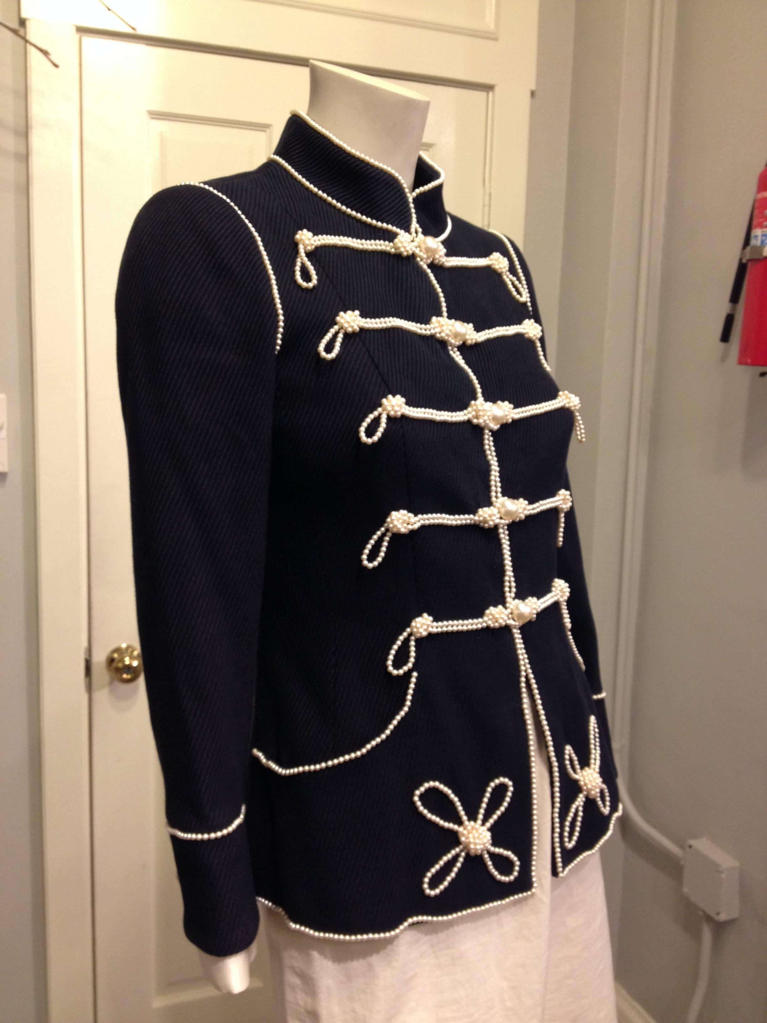 Chanel does Sgt. Pepper! This piece is an absolute show-stopper - the deep navy woven material is cut sharp with a high collar and nipped-in waist, and trimmed with a plethora of iconic Chanel pearl strands that style the piece like a marching band