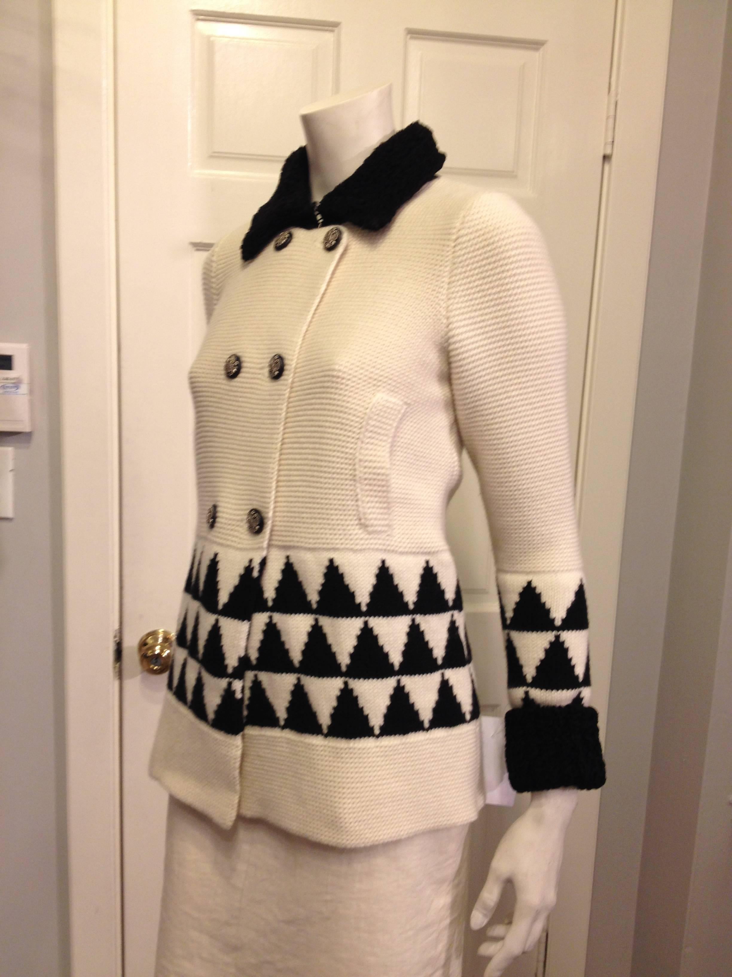This elegant sweater jacket by Chanel will keep you warm all winter long. It closes with six beautiful silver buttons and the collar and lower part of the cuffs are decorated with a fuzzy faux fur trim.  The slightly flared bottom part of the jacket