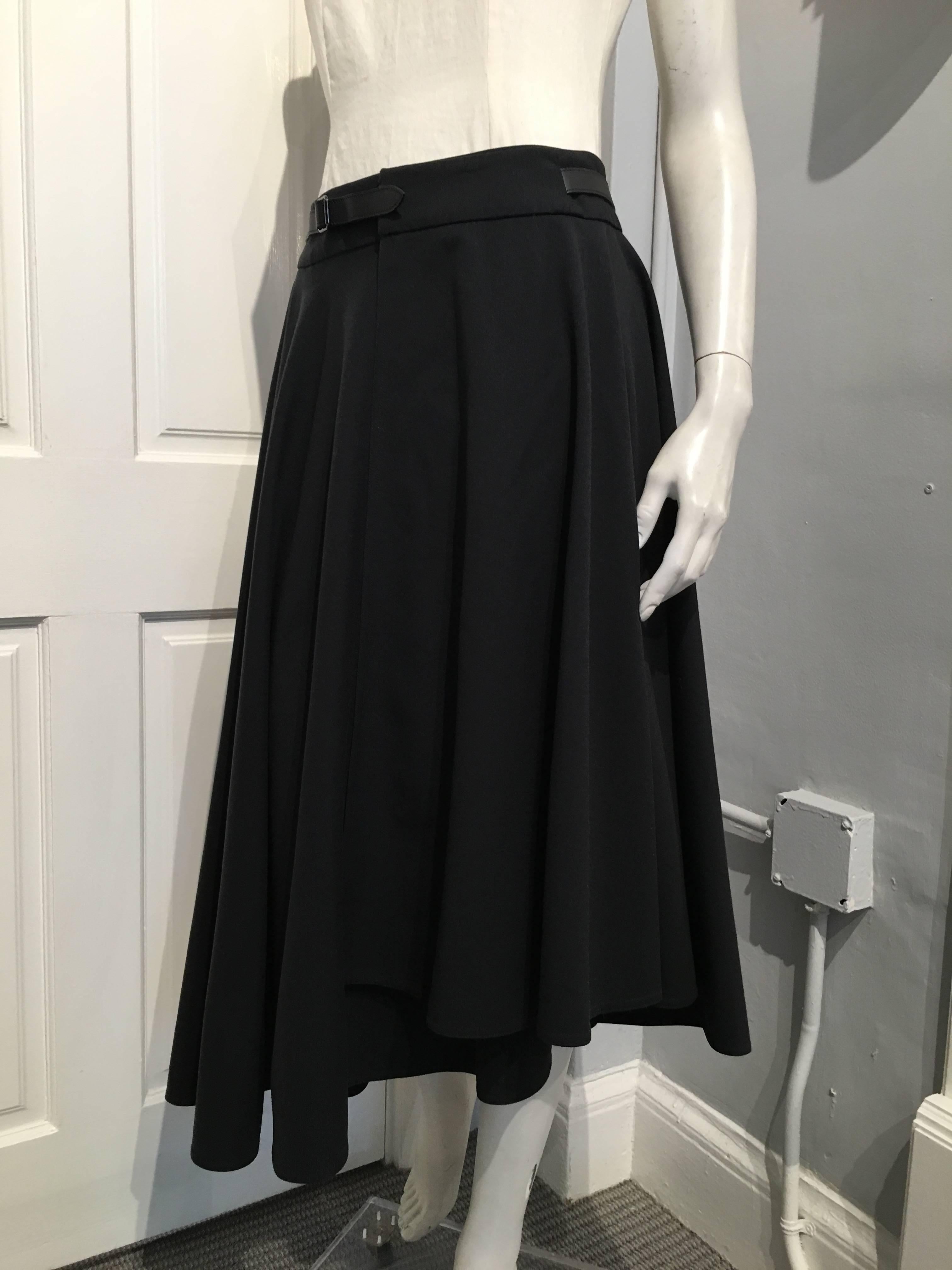 Flared Hermes black wool wrap skirt with an asymmetrical hem from the Fall 2014 collection. It has one pocket on the right side, and an adjustable calfskin belt sewn onto it.