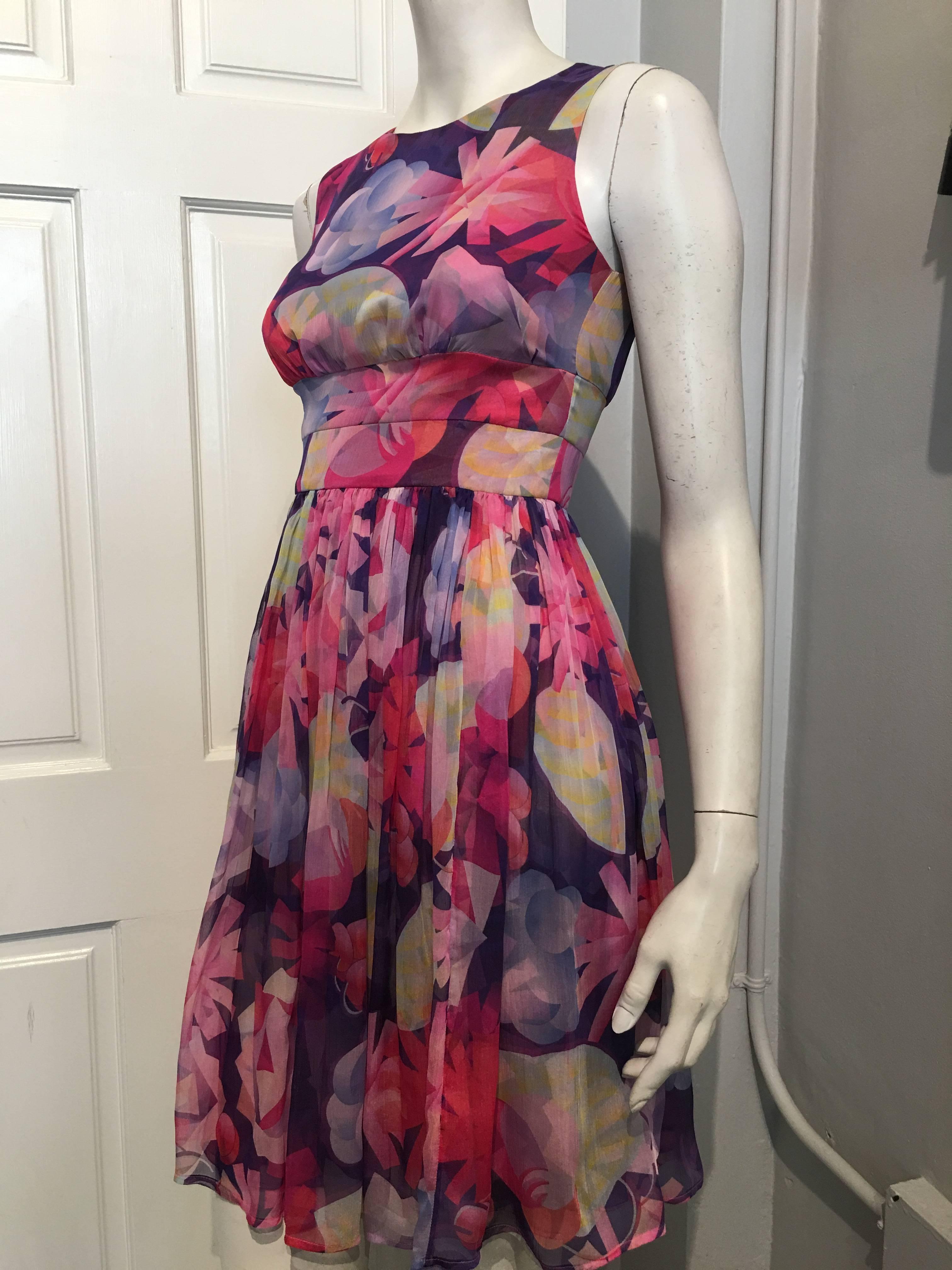 Chanel dress with a double layered full skirt and two tiered waist band with slight gathering under the bust, in a geometric floral type pattern in pink, purple and blue. 