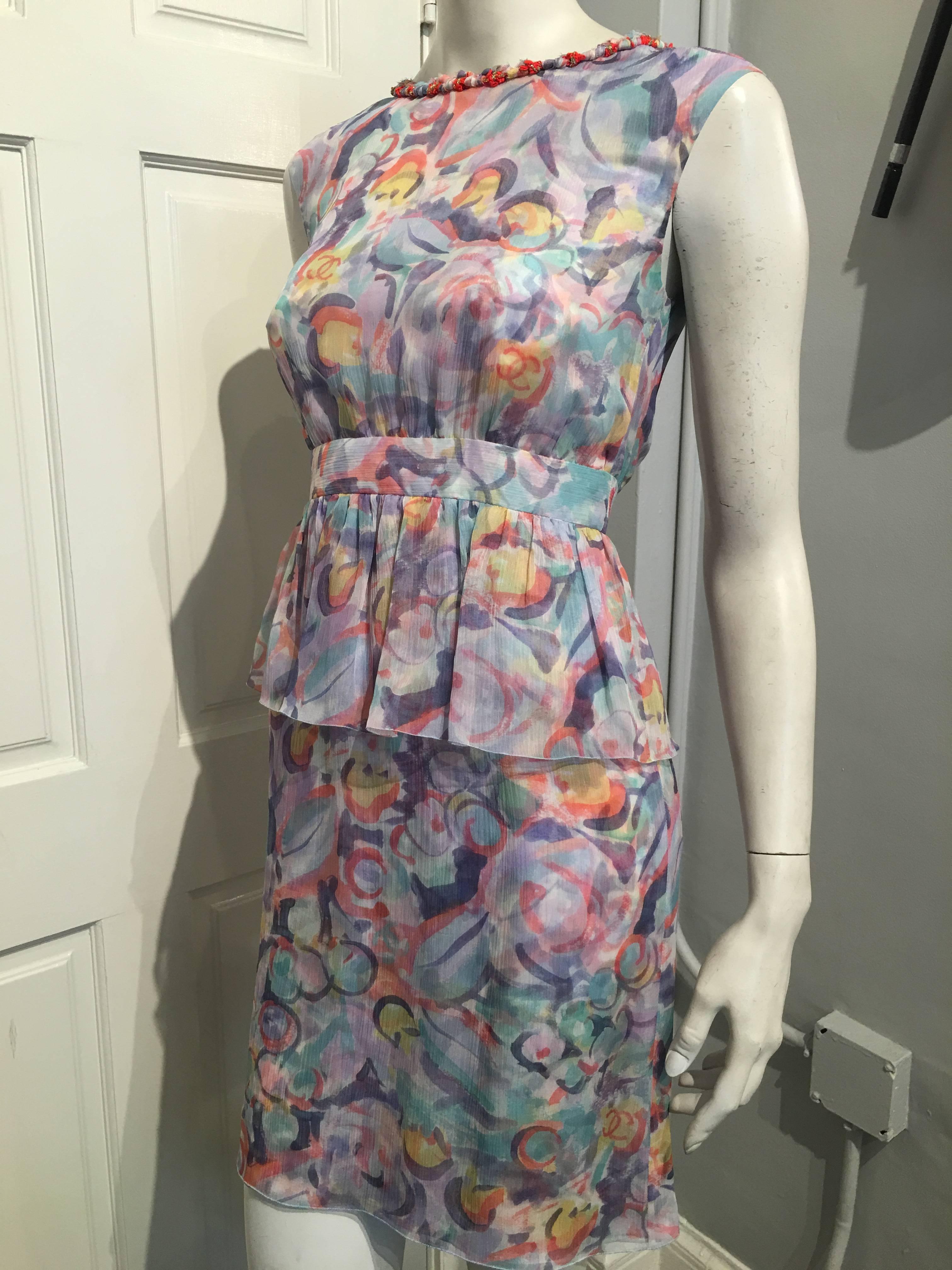 Chanel peplum dress in a pastel floral design on triple layered chiffon with a knotted ribbon accent in pastels, dark orange and gold metallic along the neckline. The dress has a fitted waistband with slightly gathered bodice, a 6.5