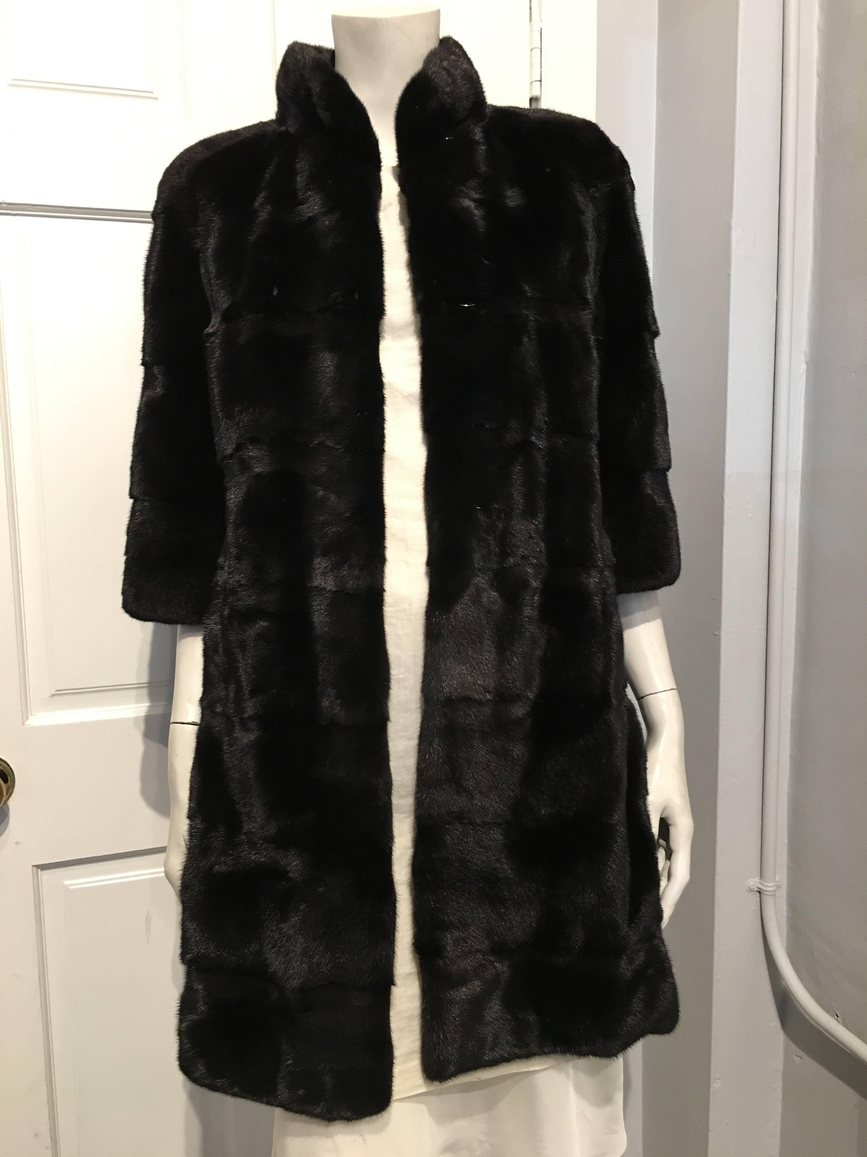 Elegant Fendi Blackglama mink knee length coat cut with horizontal pelts and 3/4 length sleeves. The coat has secure hook and eye closures, and a small stand up collar that closes at the nape of the neck. We assume it is a size 6, as the size tag