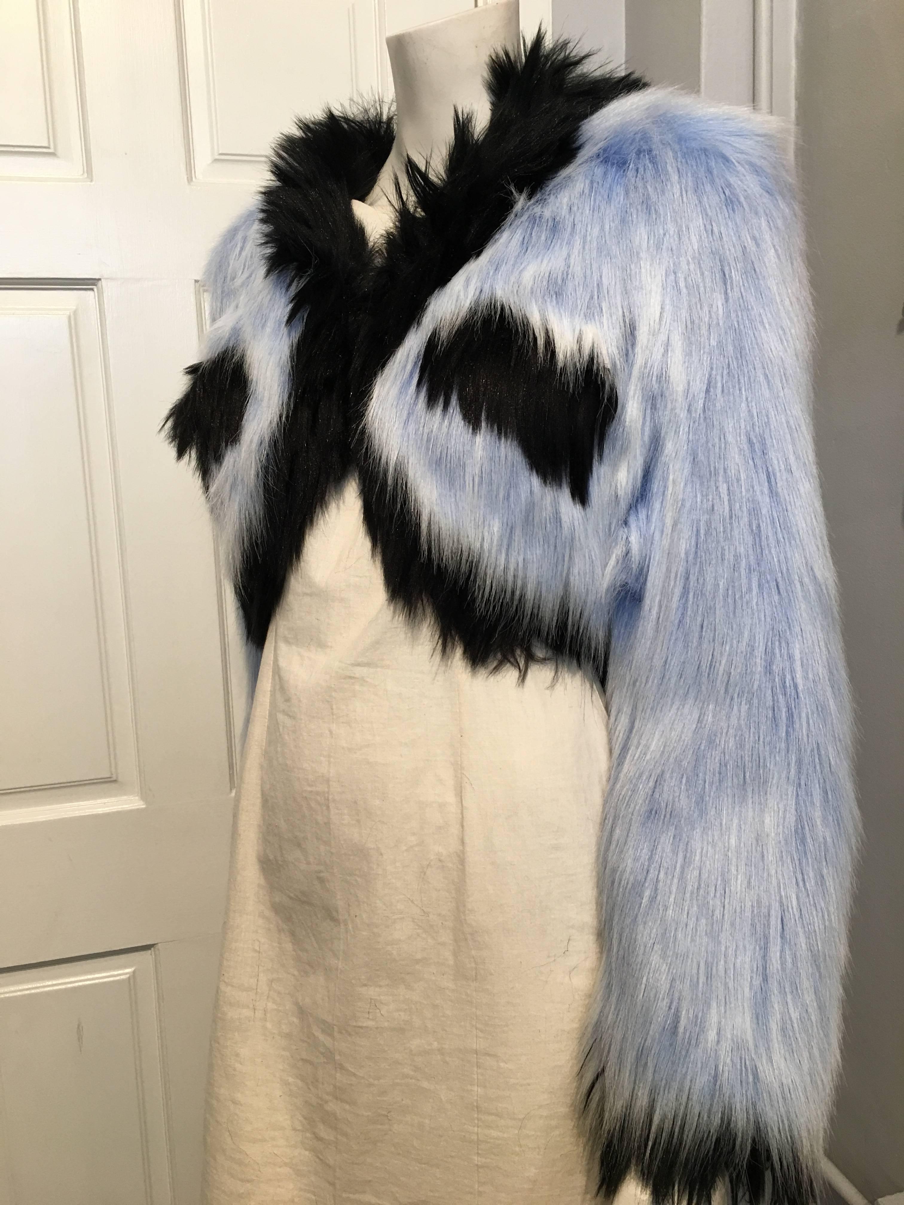 Chanel faux fur cropped jacket in blue and black. it closes with a single hook and eye. The black silk lining features the brand name in large white text.