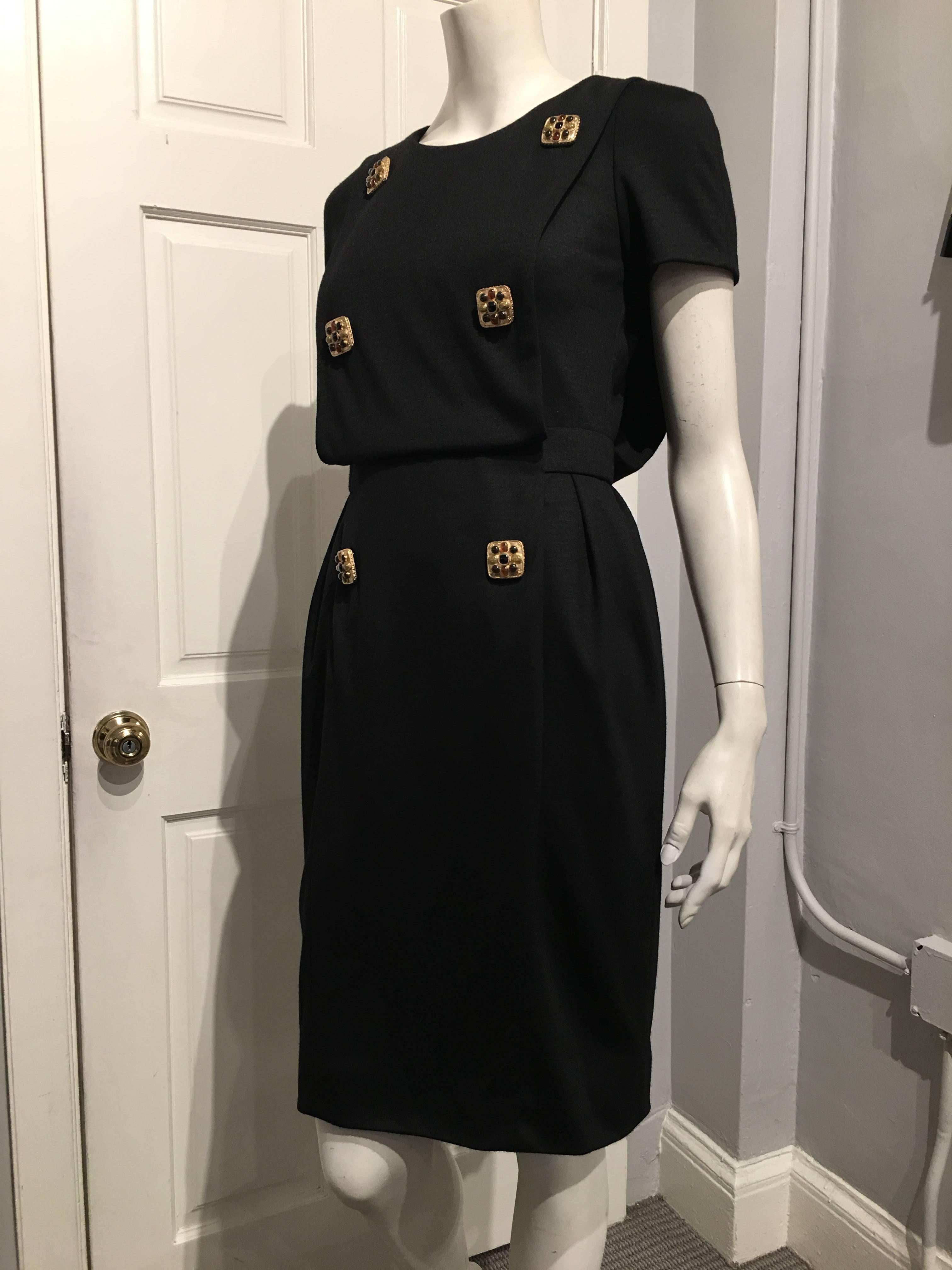 Chanel black wool dress with front and back paneling. The dress has a pocket that opens at either side and features six gripoix buttons in rust, grey, gold and black set on a gold metal backing down the front.

This piece is brand new with tags.