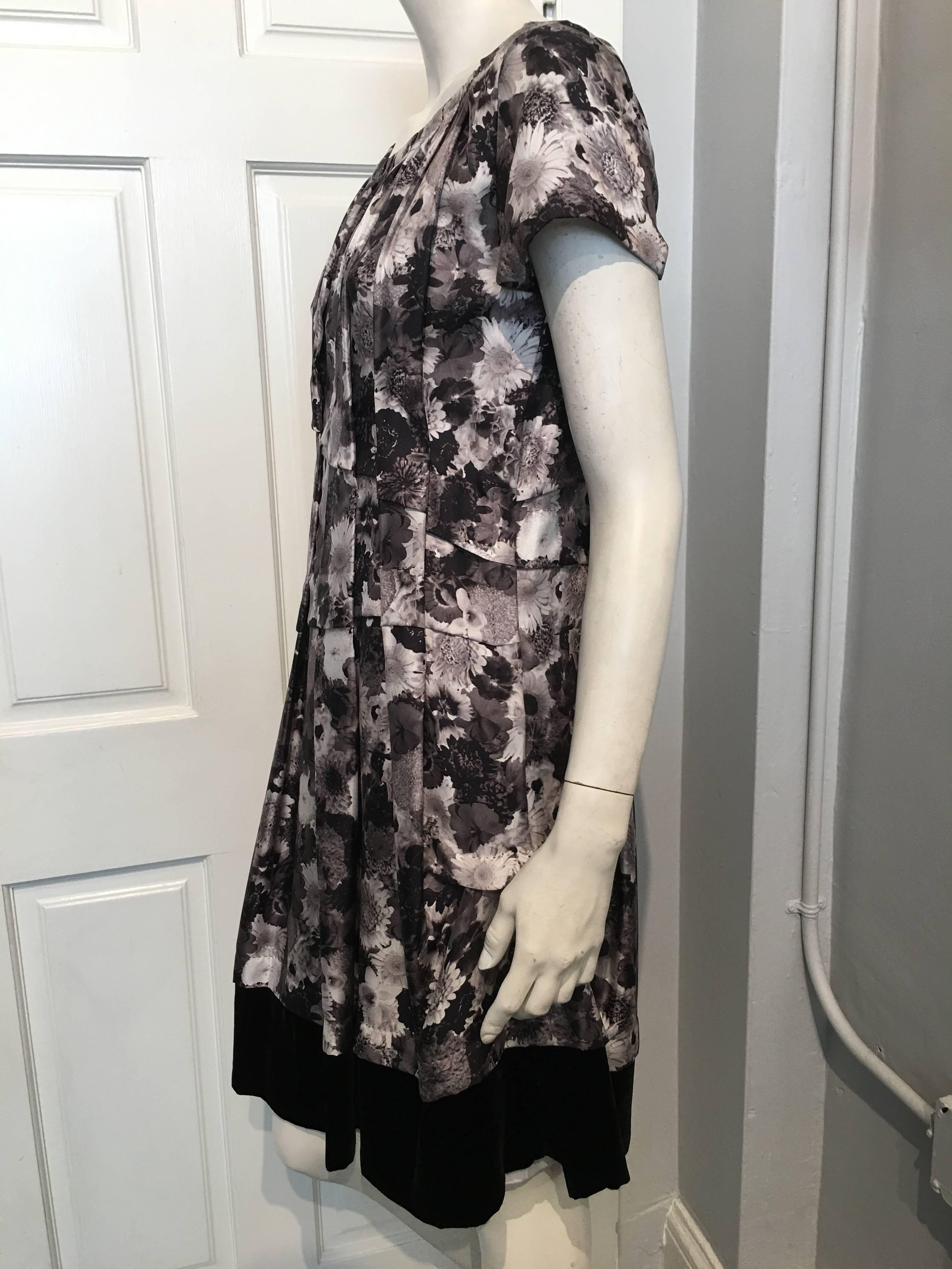 Louis Vuitton grey short sleeve floral dress with black velvet trim at hem. The dress has a sheer floral lining in the same grey color palette, and closes along the left side with a set of snap closures. 